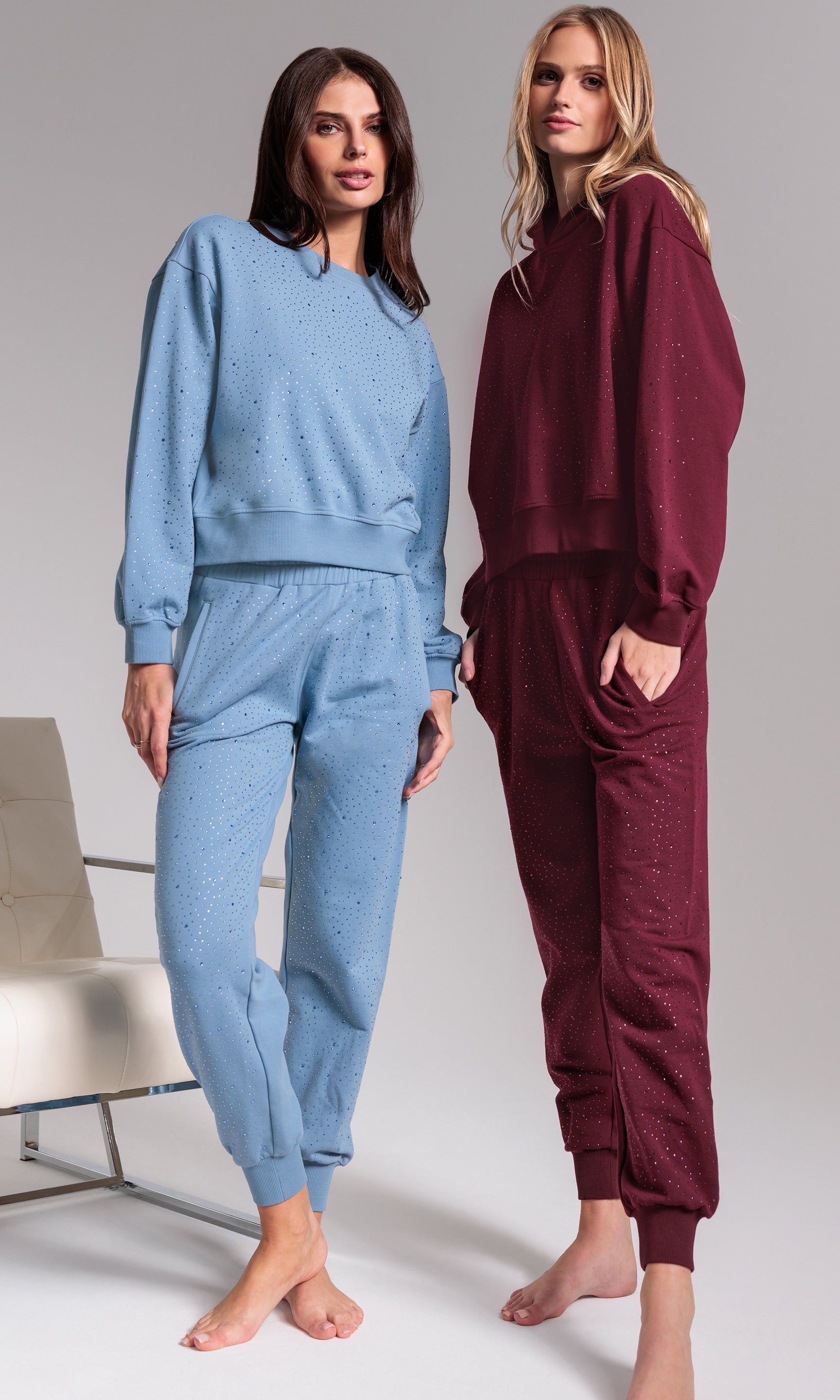 Two women wearing matching blue and maroon tracksuits on a plain background