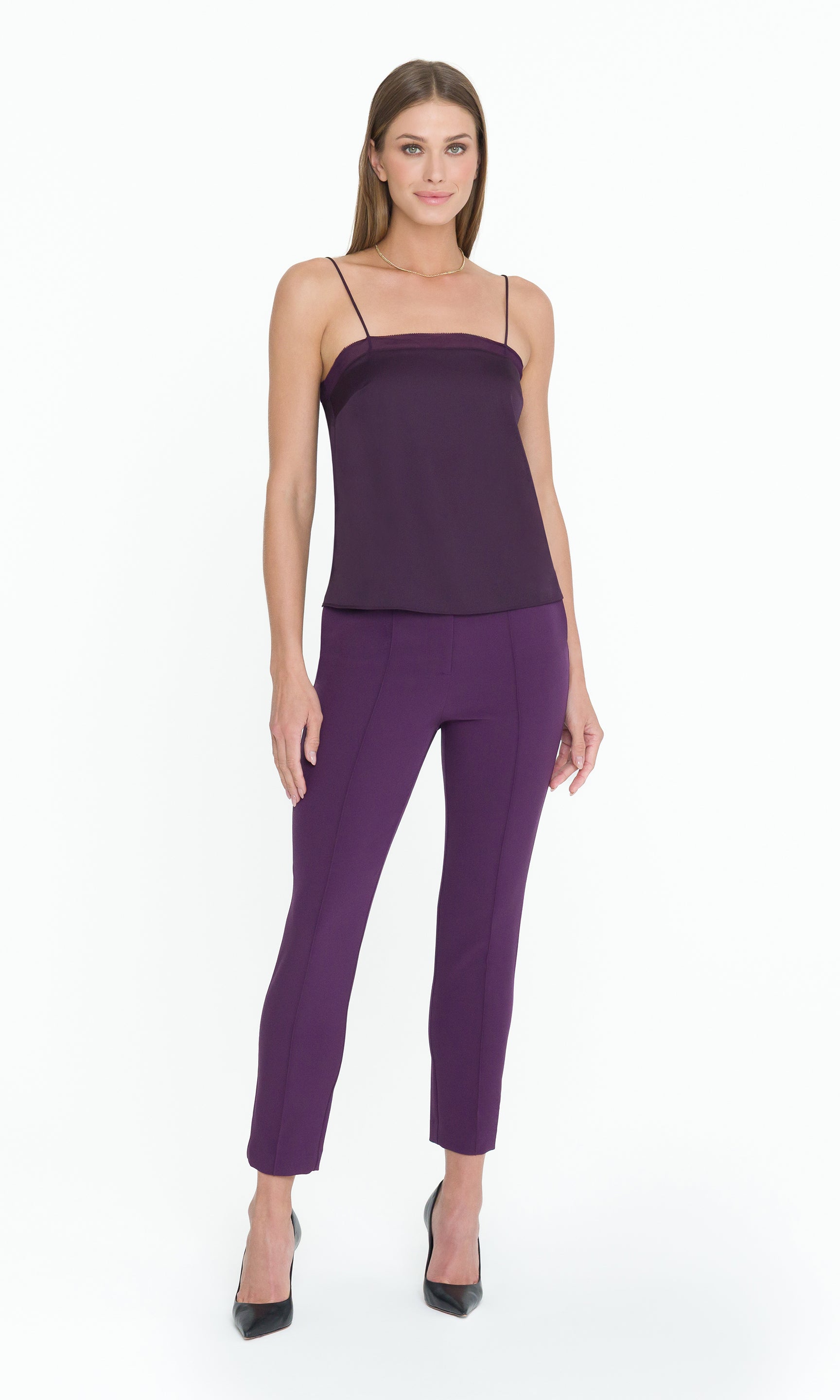 Full body image of woman wearing a purple top and pants on a white background