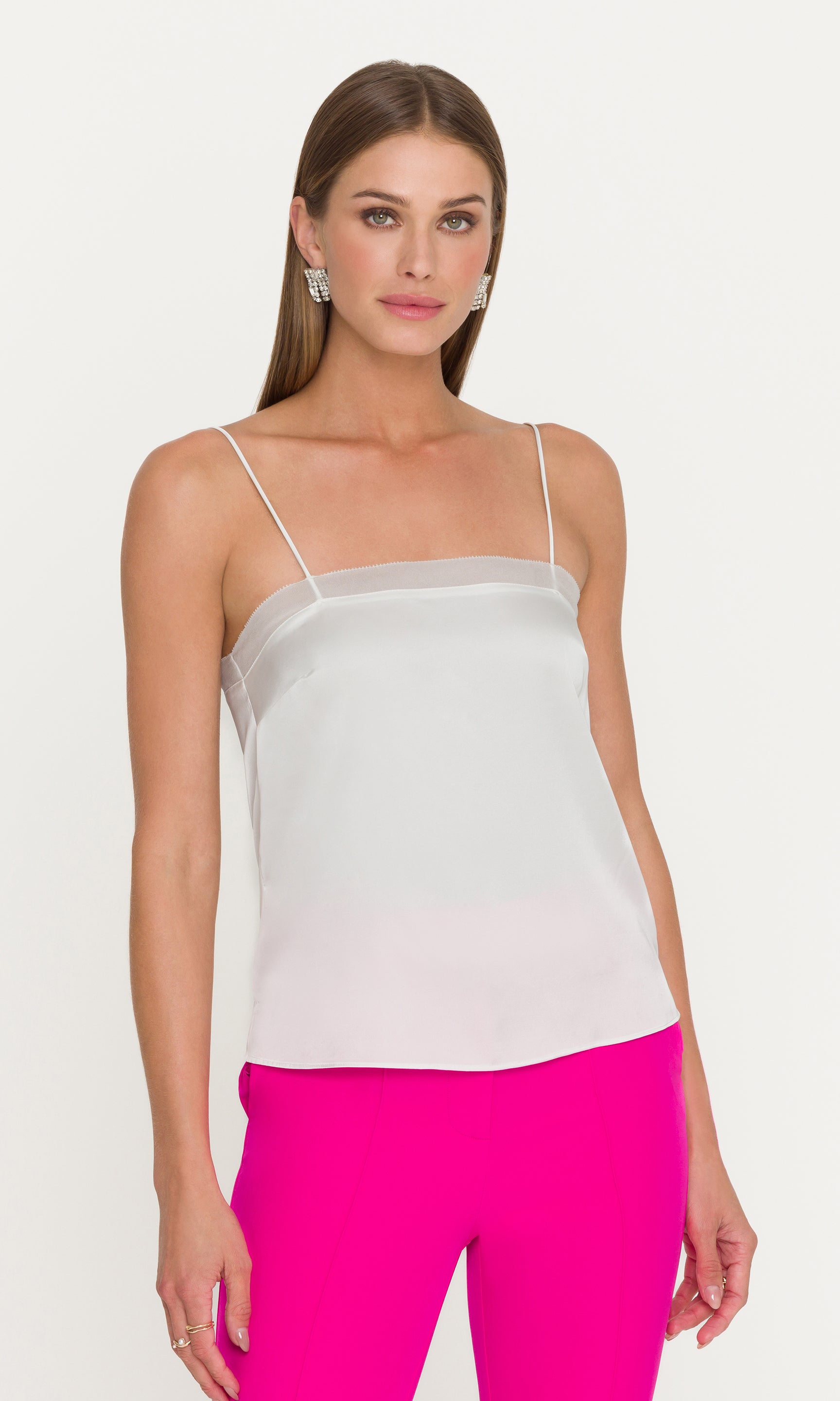 3/4 view of model wearing a white cami and pink pants on a white background