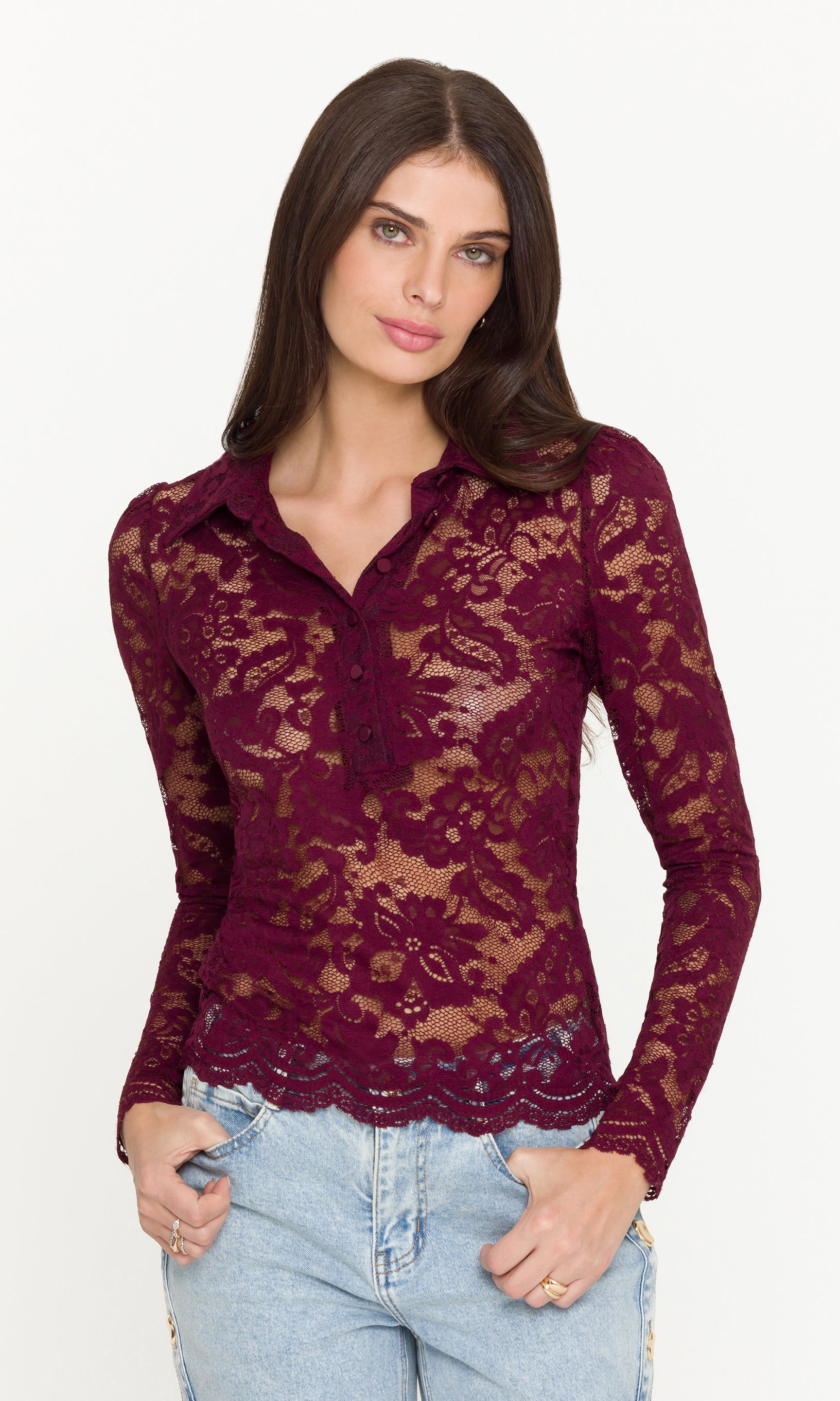 Woman wearing a burgundy lace long sleeve top with her hand on her hip
