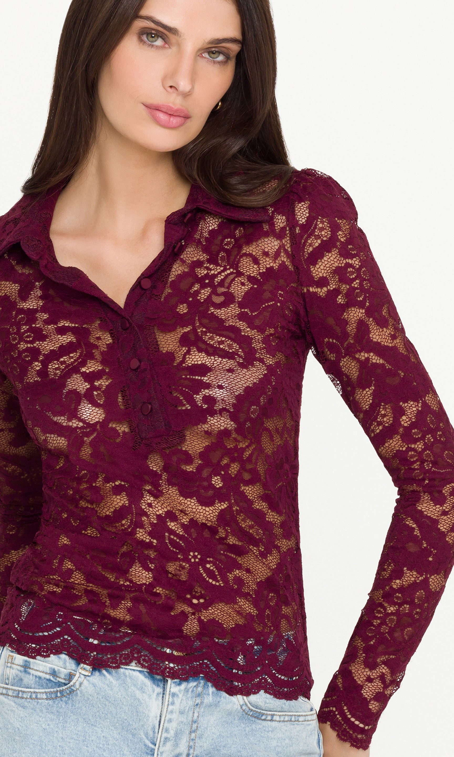 Close-up of woman wearing a burgundy lace long-sleeve top against a white background