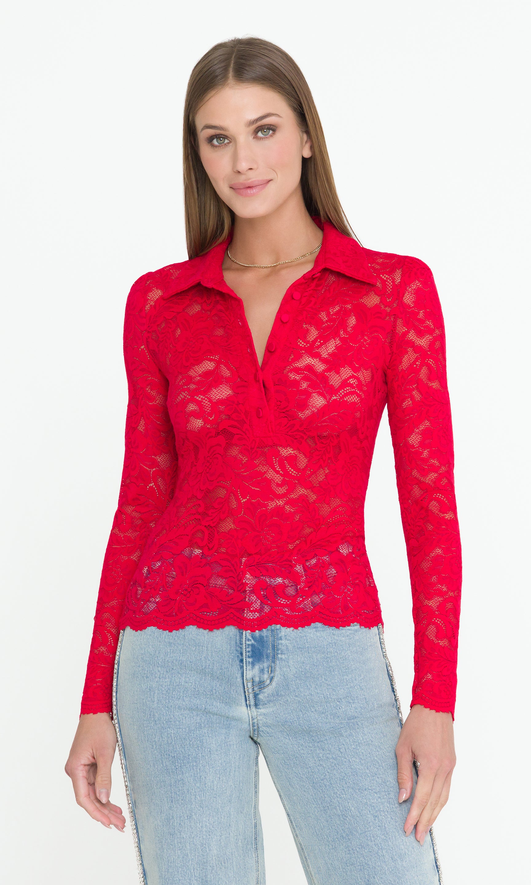 Woman wearing a red lace longsleeve top and light blue jeans on a white background