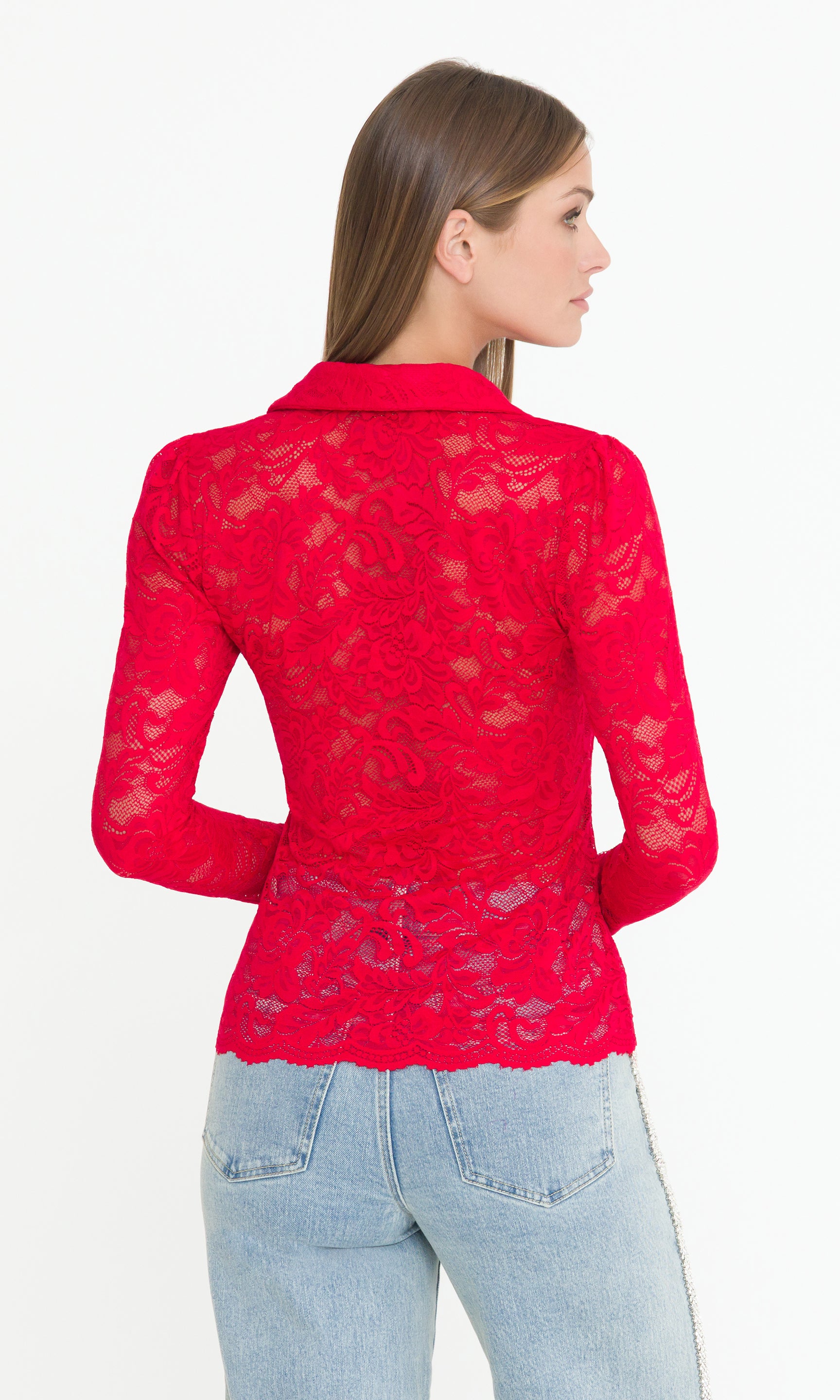 Back view of woman wearing a longsleeve red lace top and light blue jeans on a white background