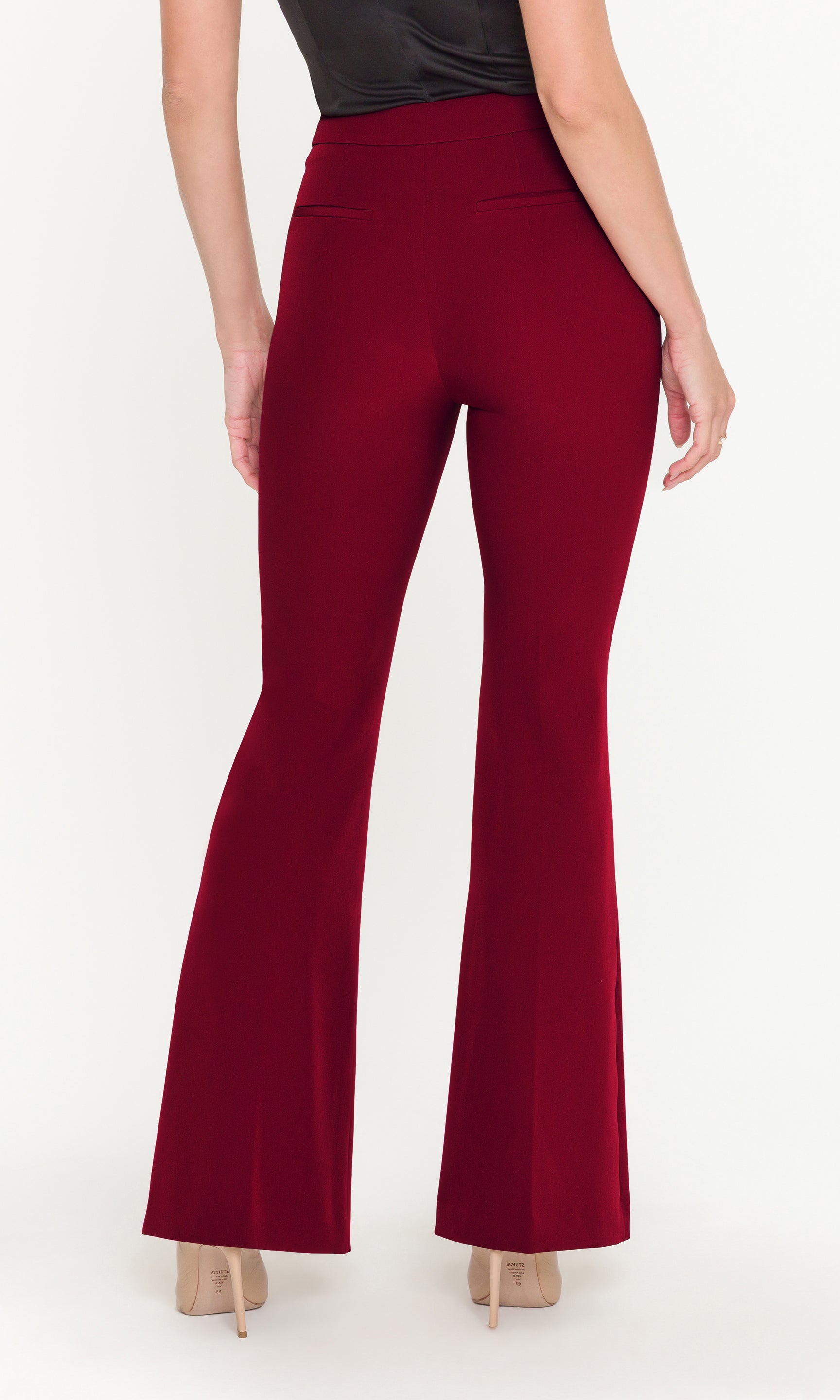 Back view of red flared pants worn by a person on a white background