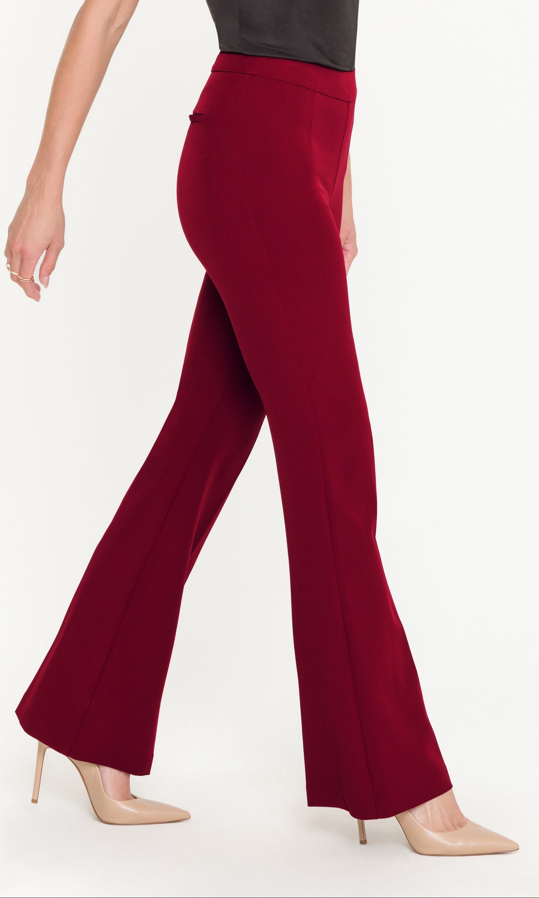 Side view of red flared pants worn by a person on a white background