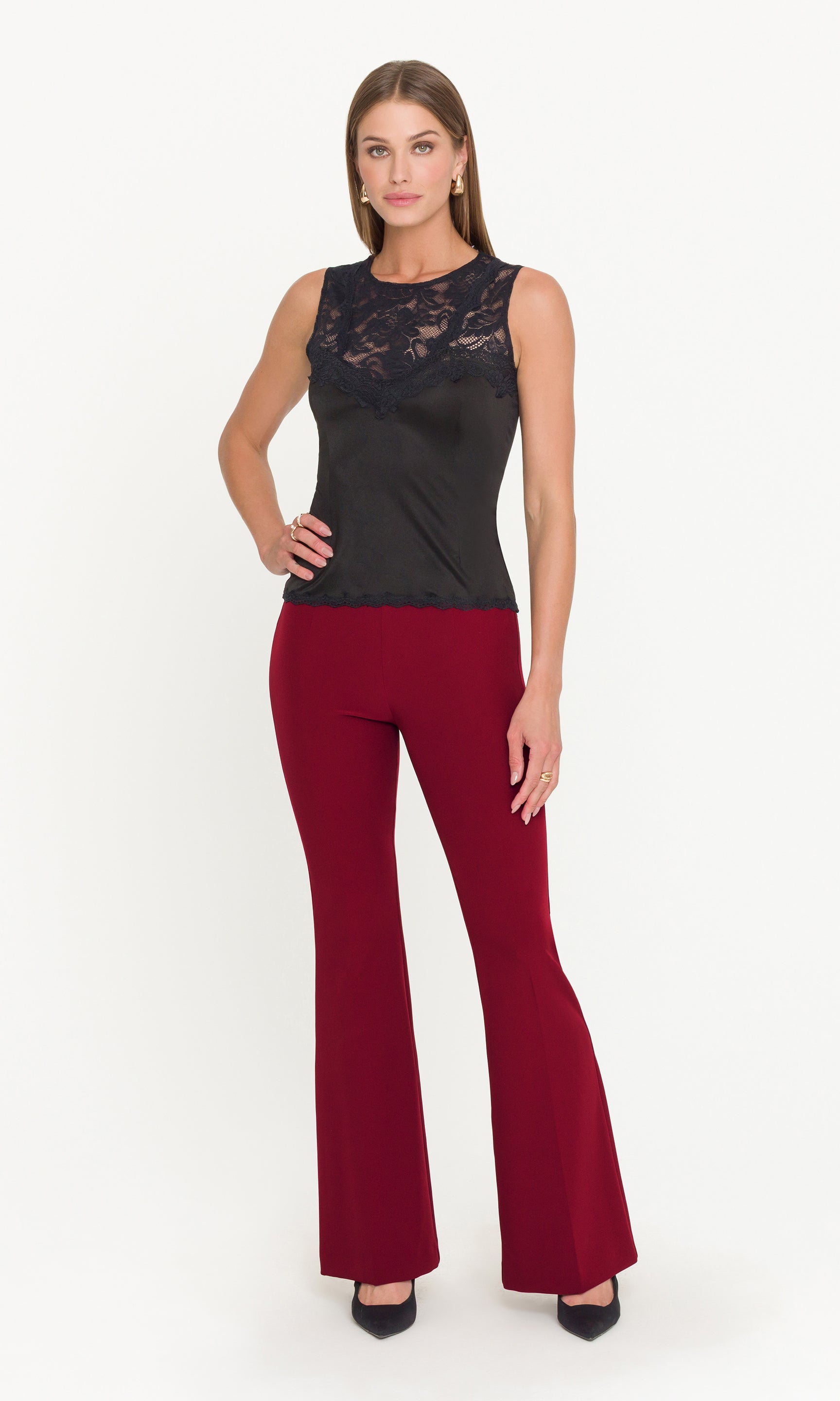 Woman wearing a black lace top and red flared pants on a white background