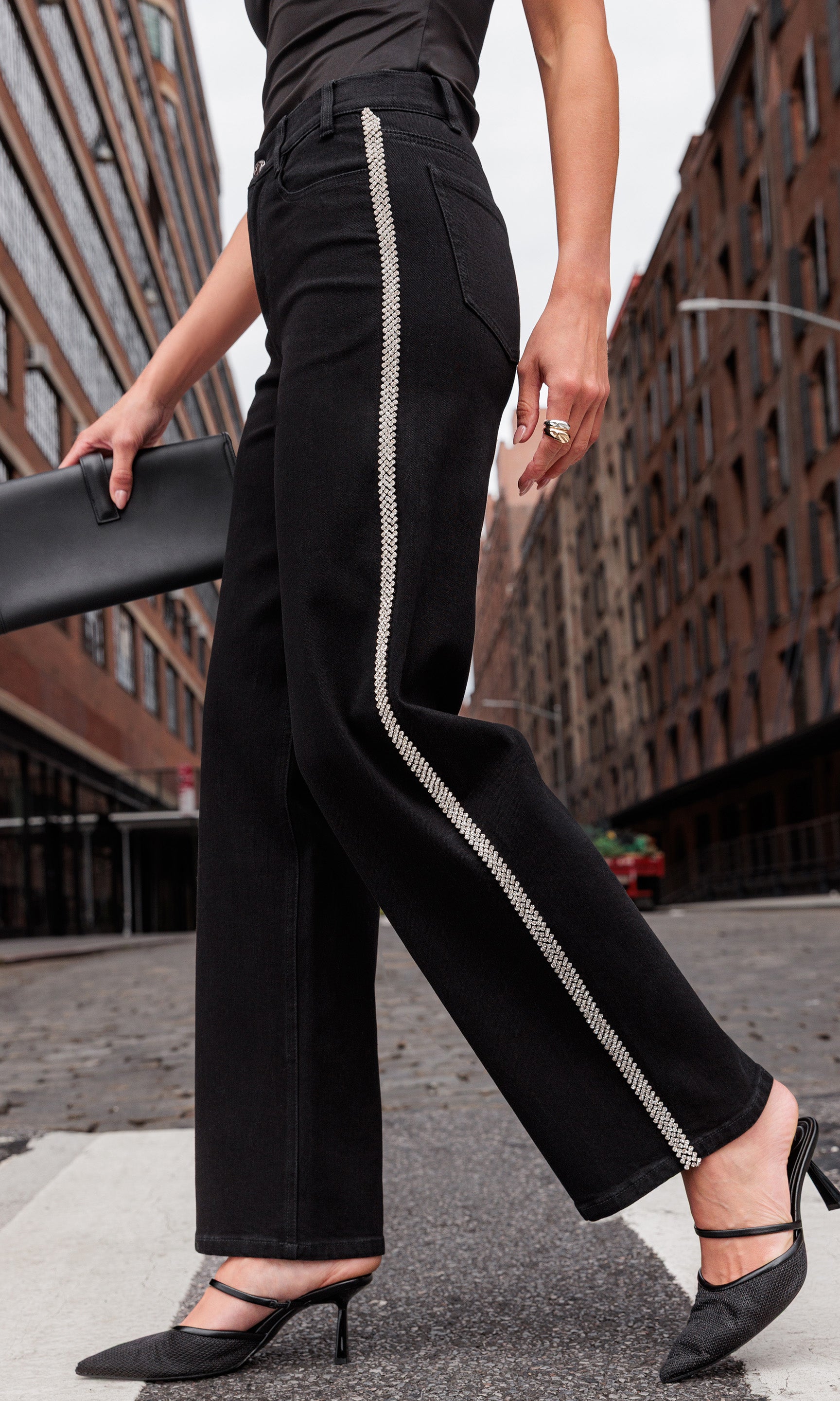 Person wearing black jeans with crystal embellishments walking on a city street