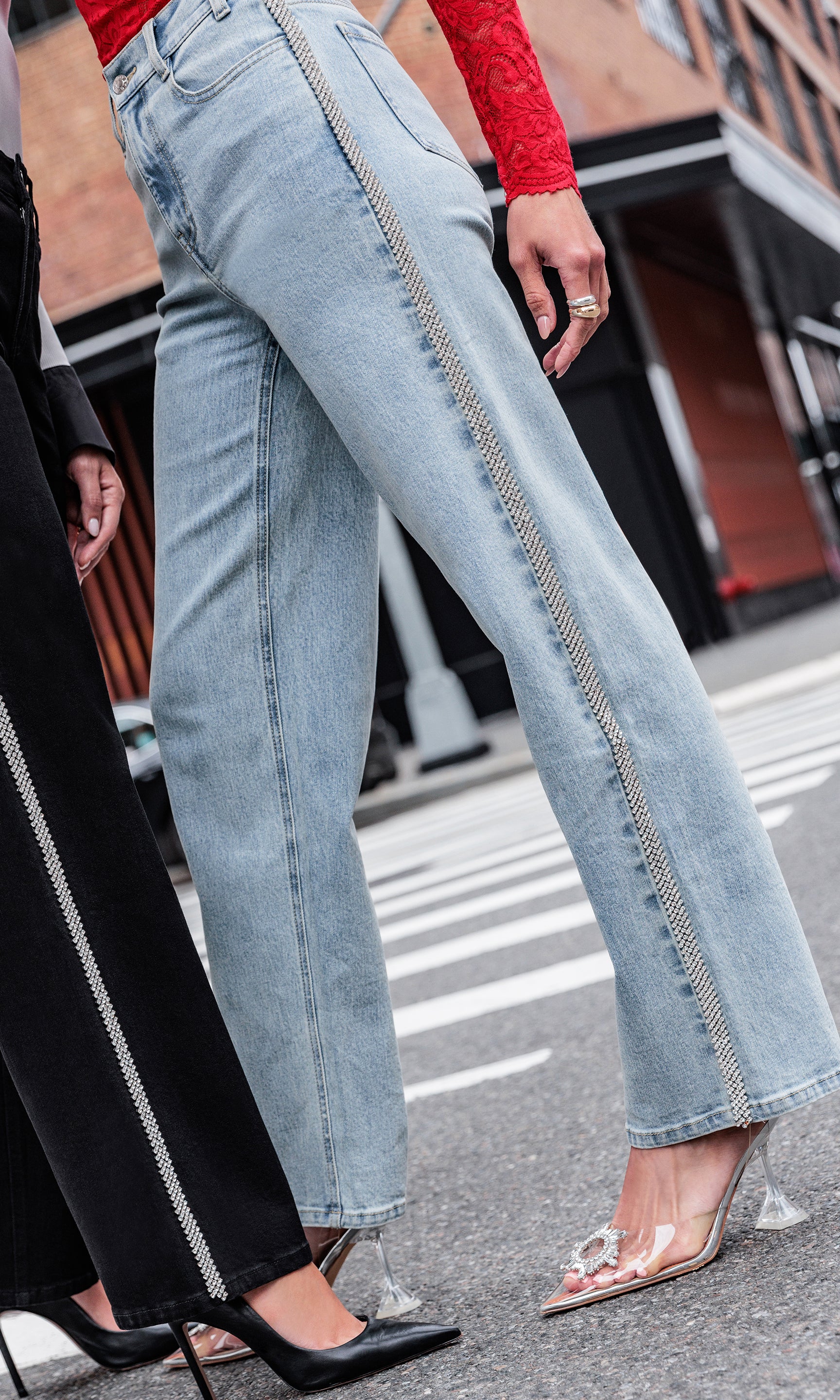 Person wearing light blue jeans on a street with blurred background