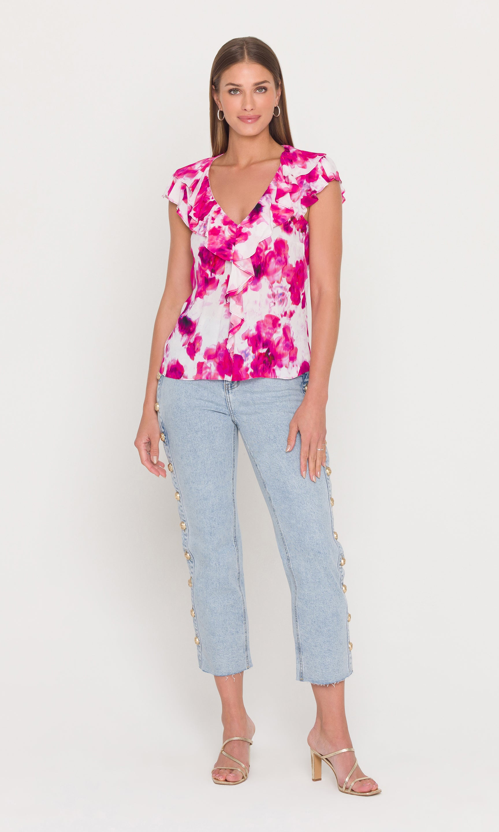 Full body image of woman wearing a pink floral top and light blue jeans on a white background