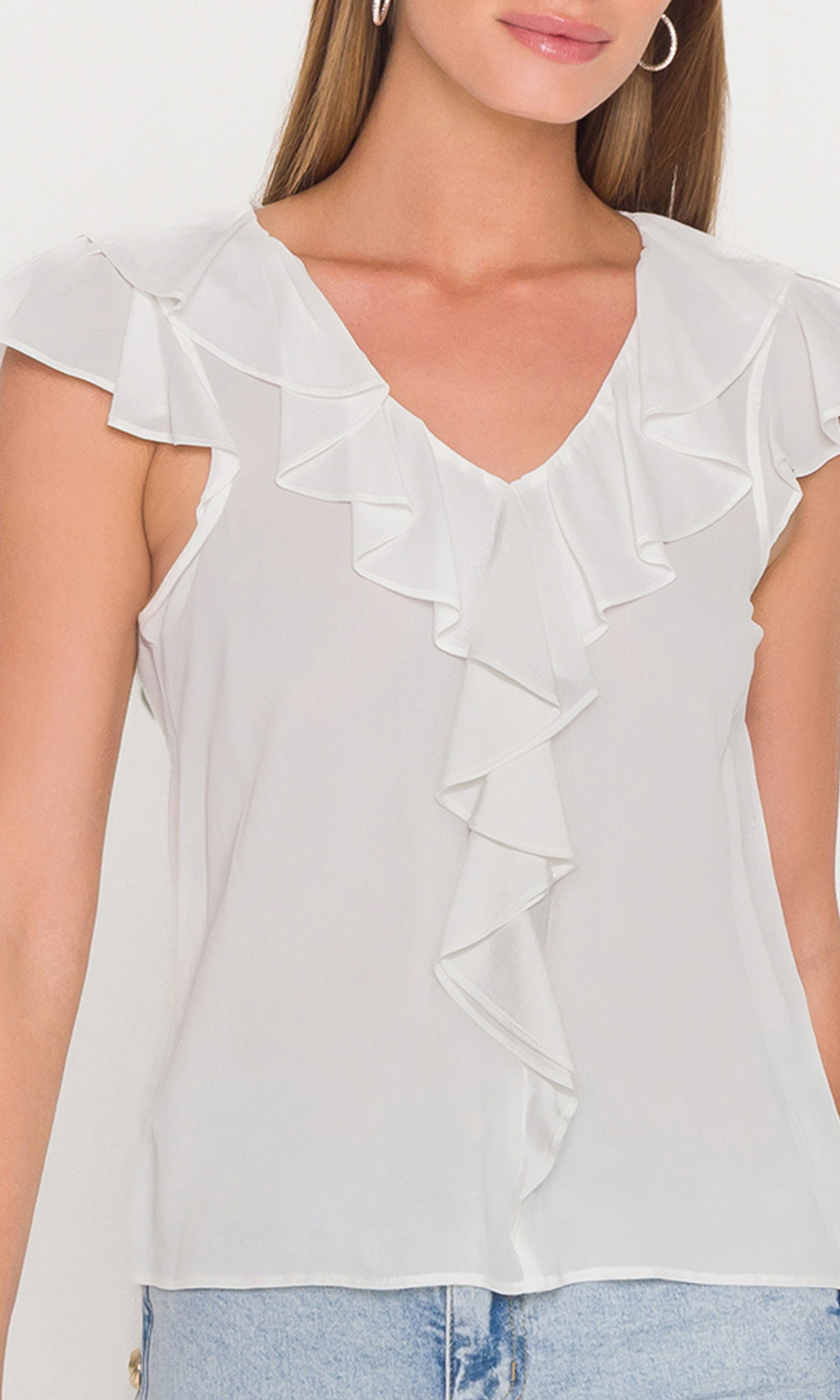 Close-up of white ruffled blouse worn by a person on a white background