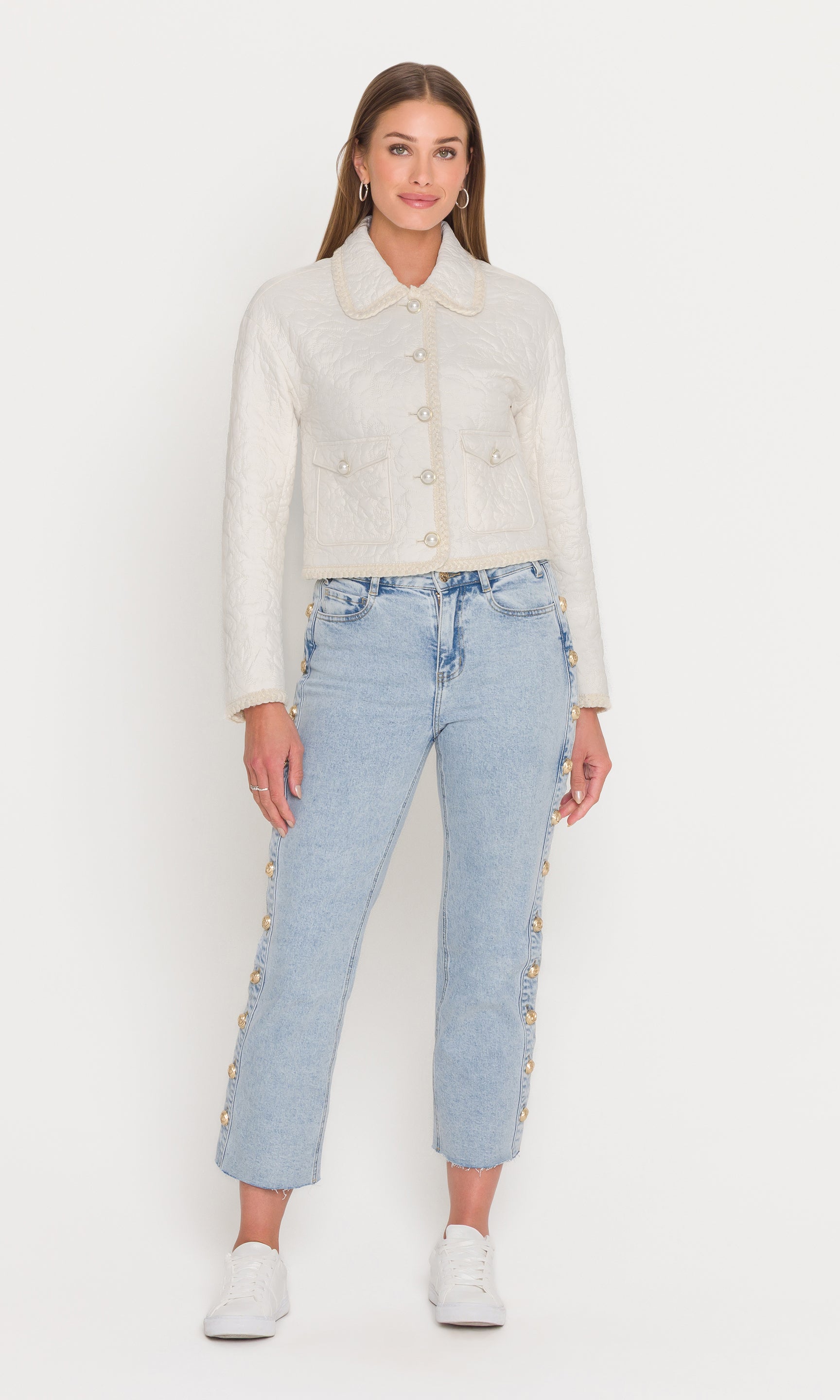 Full body image of woman wearing a white textured jacket and light blue jeans on a white background