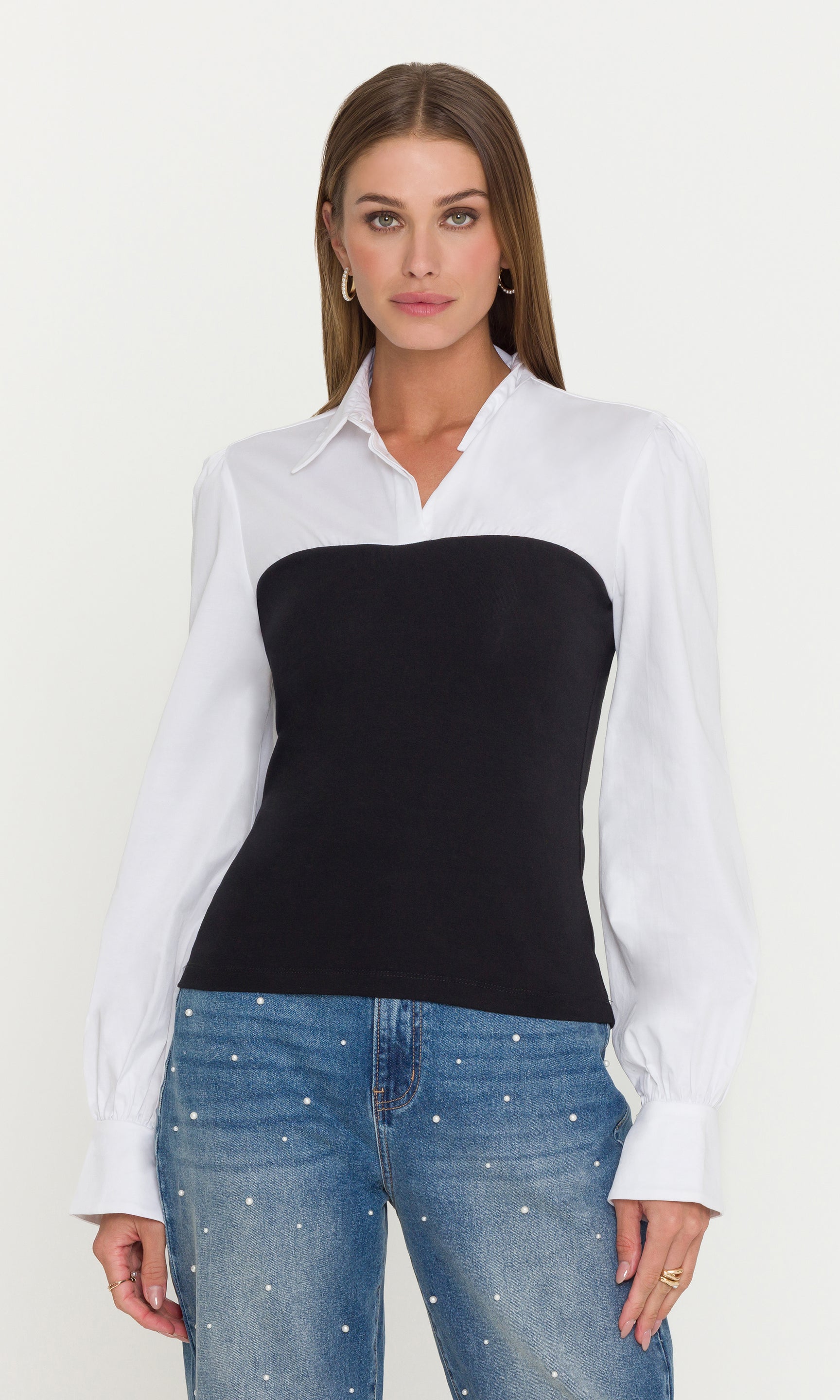 Woman wearing a white shirt over a black top with blue jeans on a white background