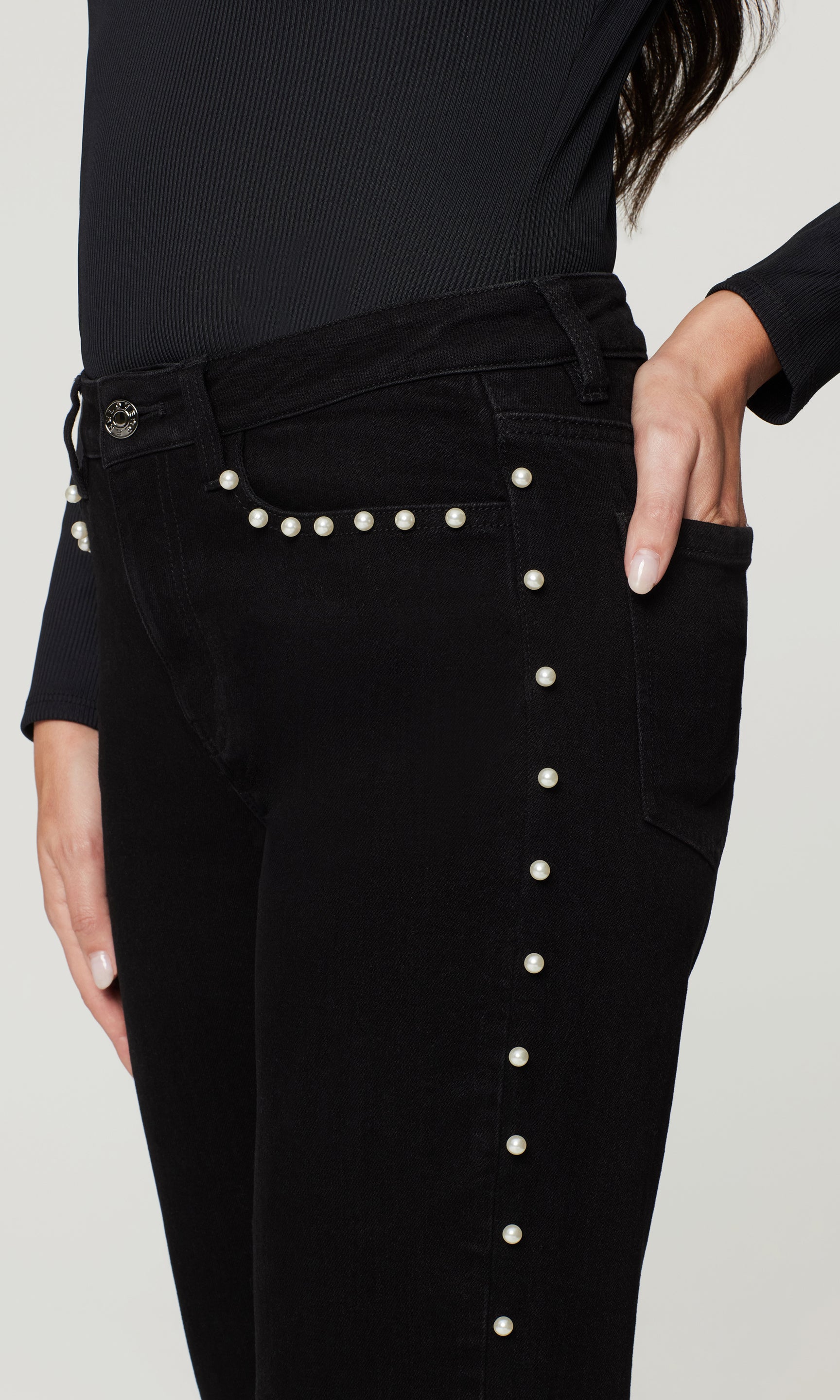Black pants with pearl buttons on a plain background