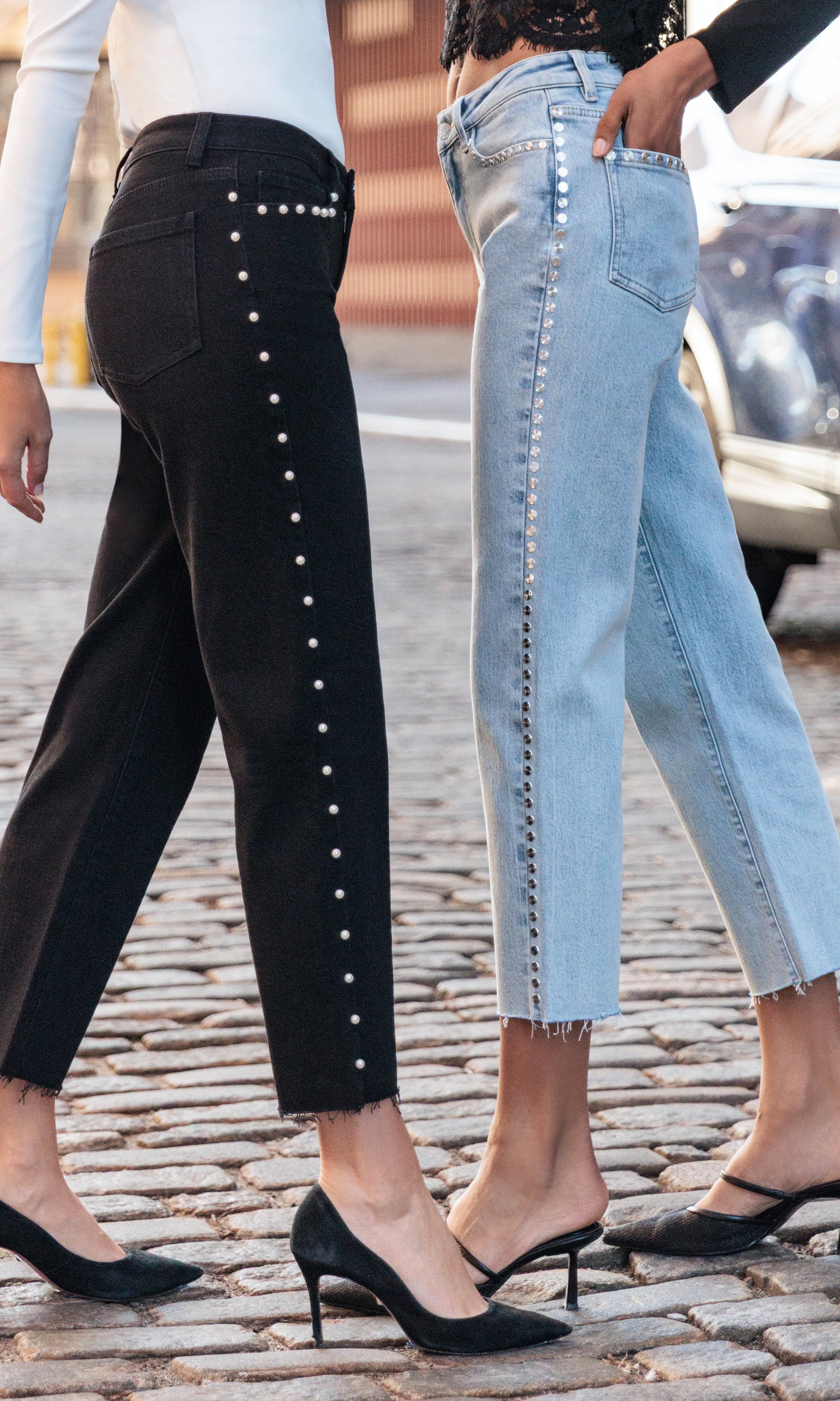 Two pairs of pants with decorative elements on a cobblestone street.
