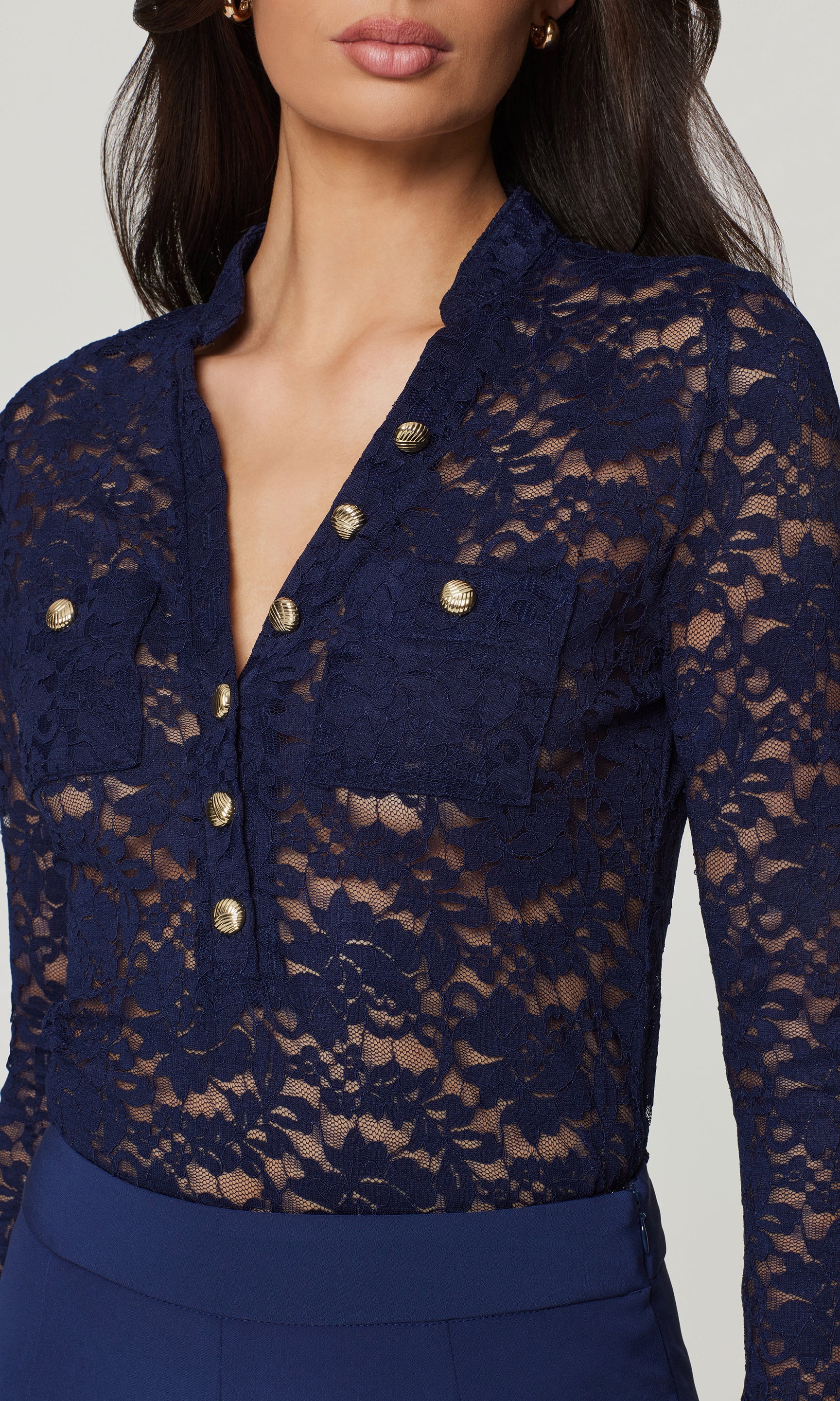 Close-up of navy lace top with gold buttons on a plain background