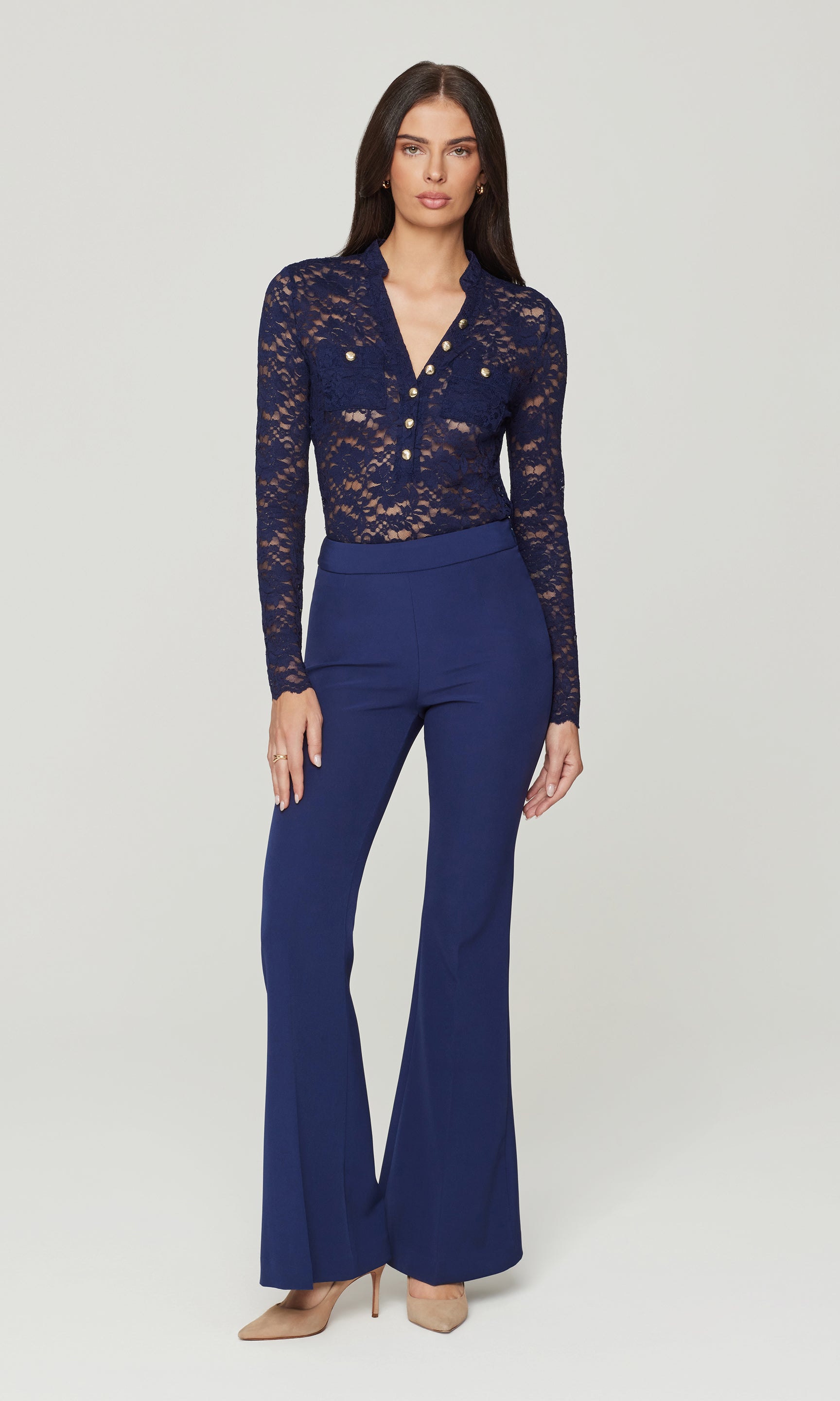 Woman wearing a navy lace top and flared pants on a white background