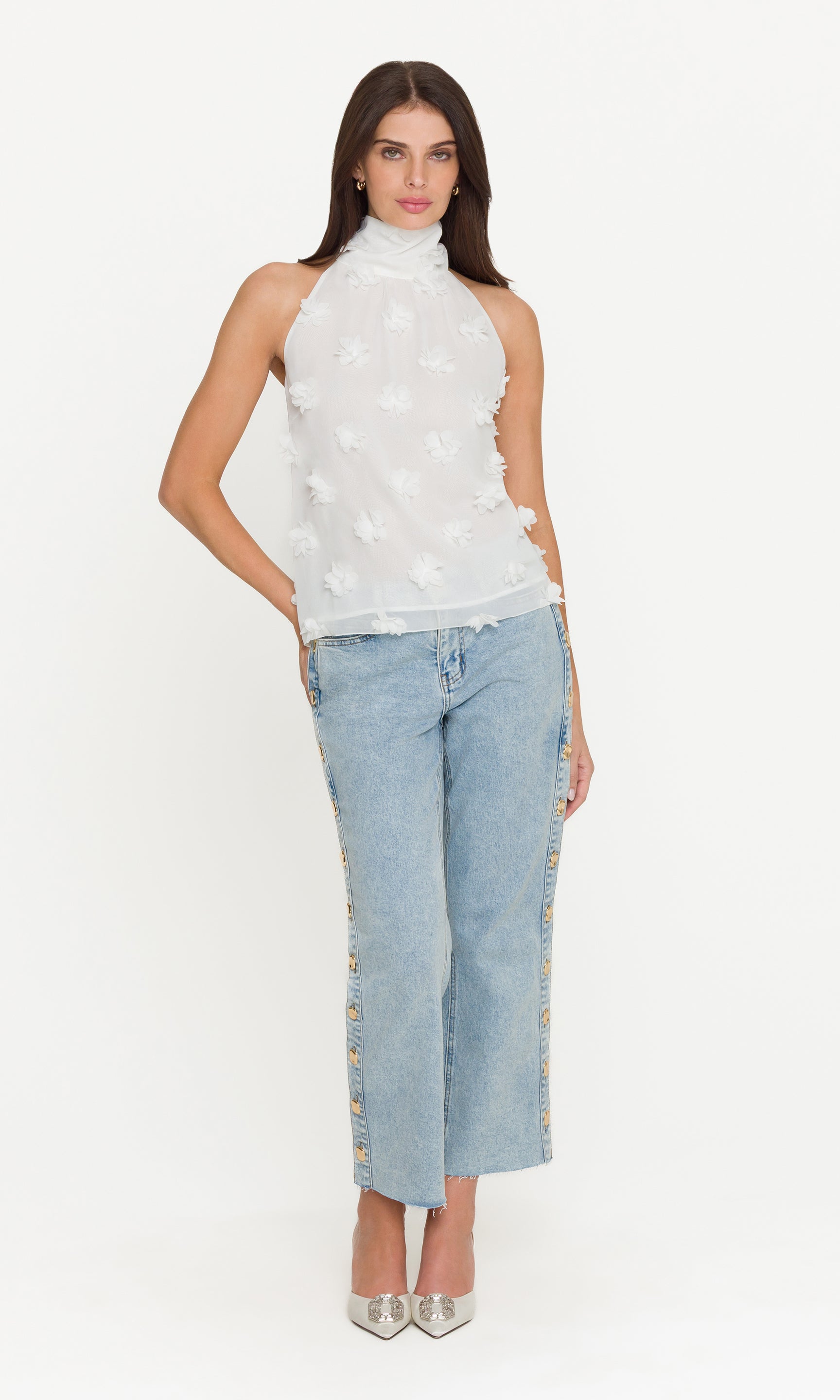 Woman wearing a white sleeveless top and light blue jeans on a white background