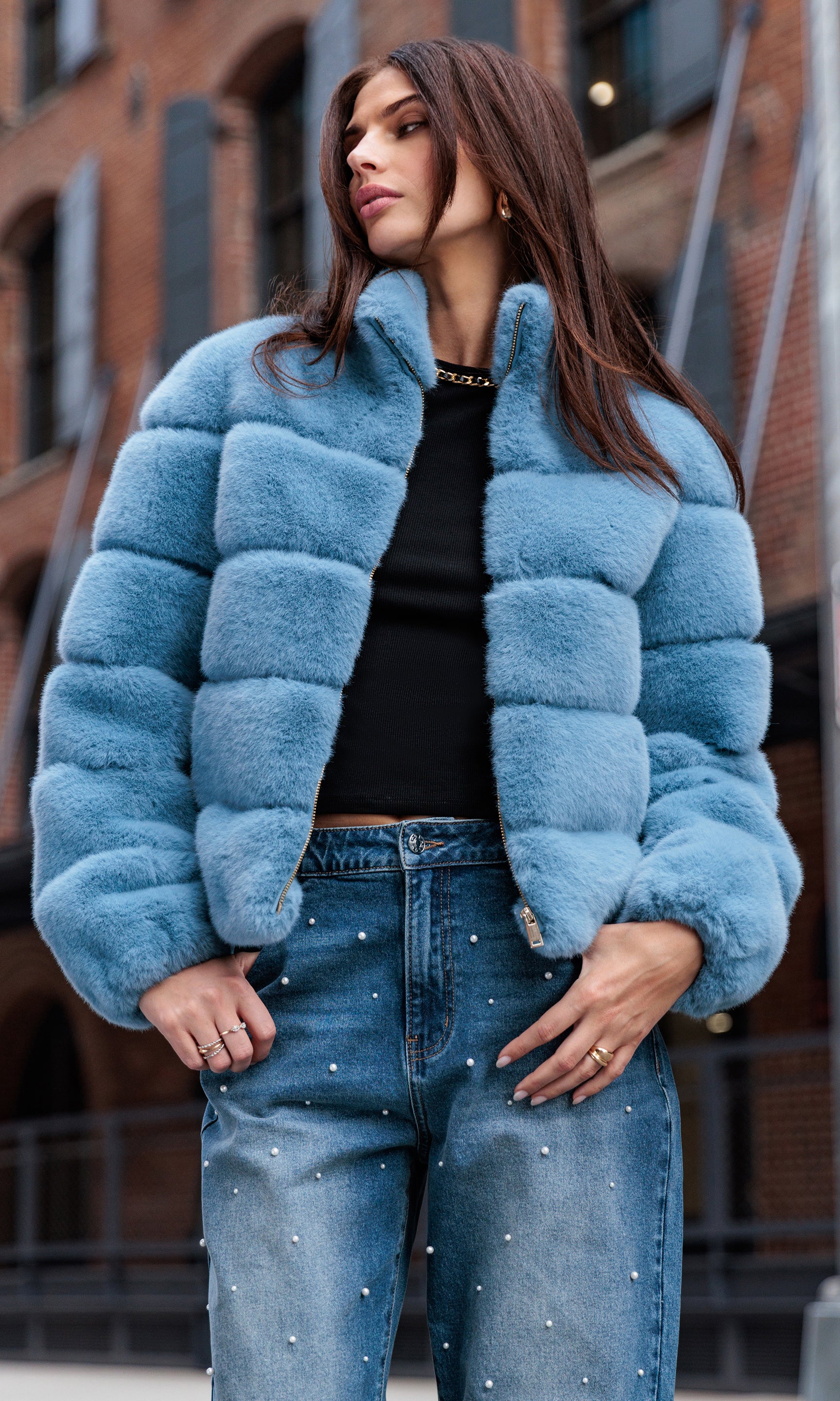 Woman wearing a blue faux fur jacket and jeans in an urban setting