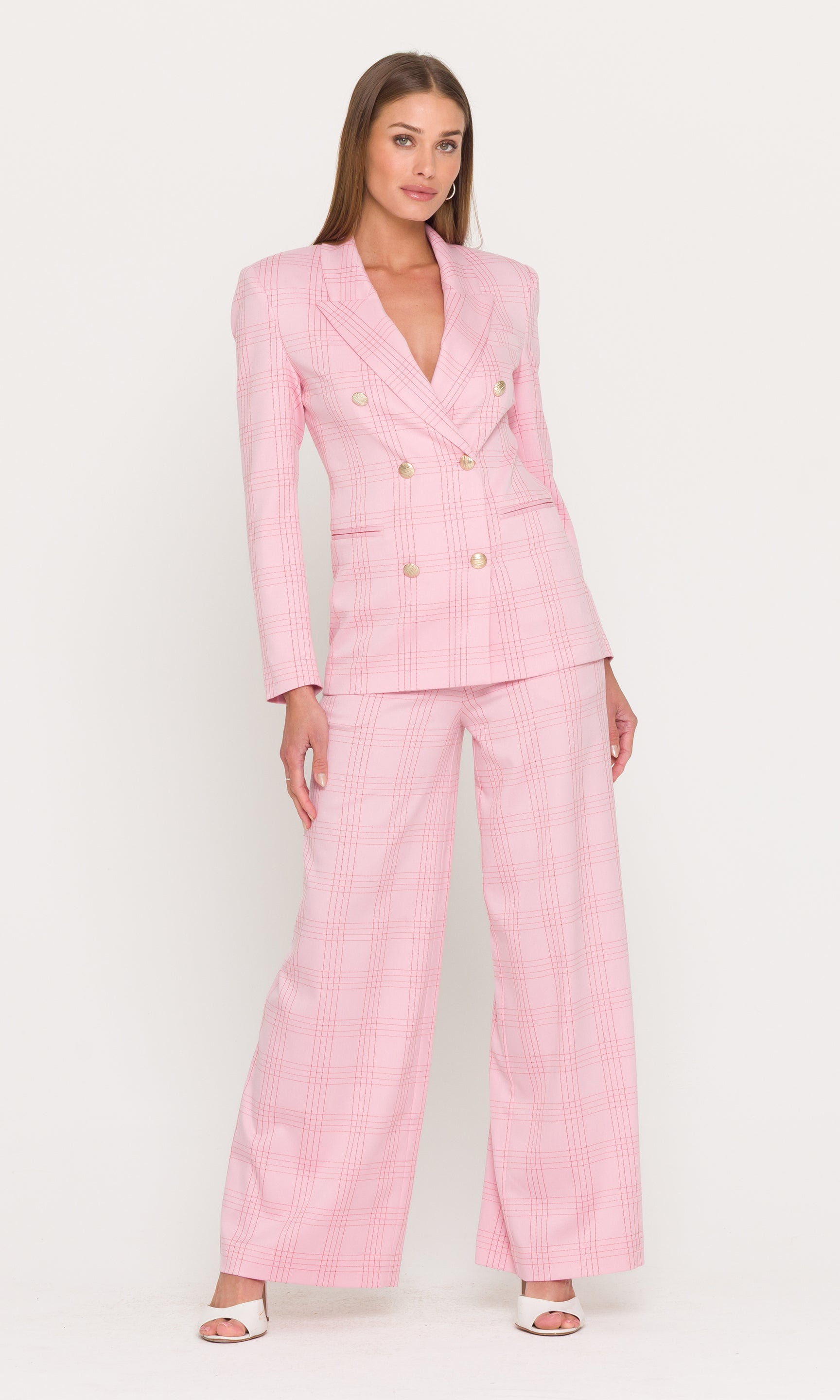 Full body image of woman wearing a pink checkered suit on a white background