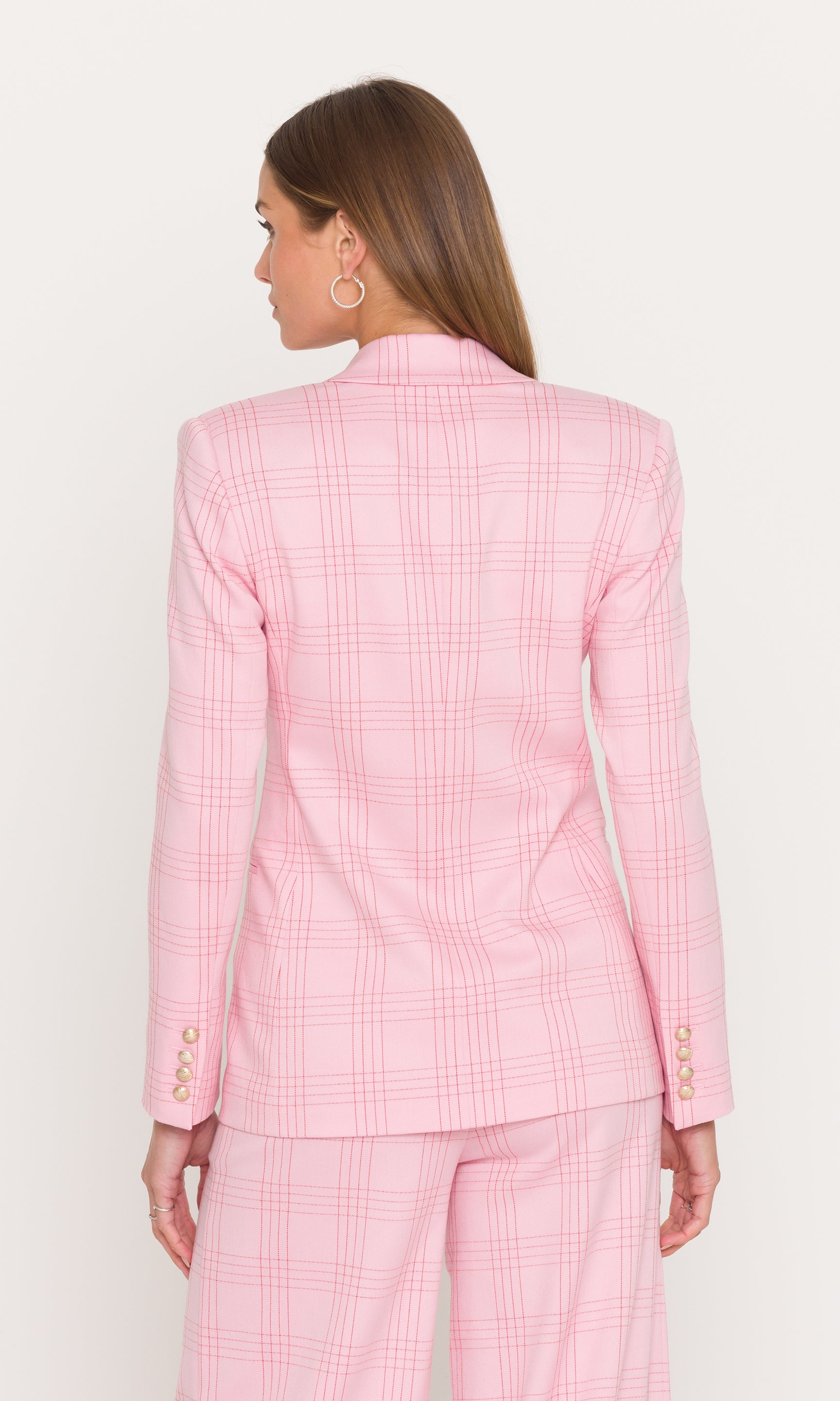 Back view of woman wearing a pink checkered suit on a white background