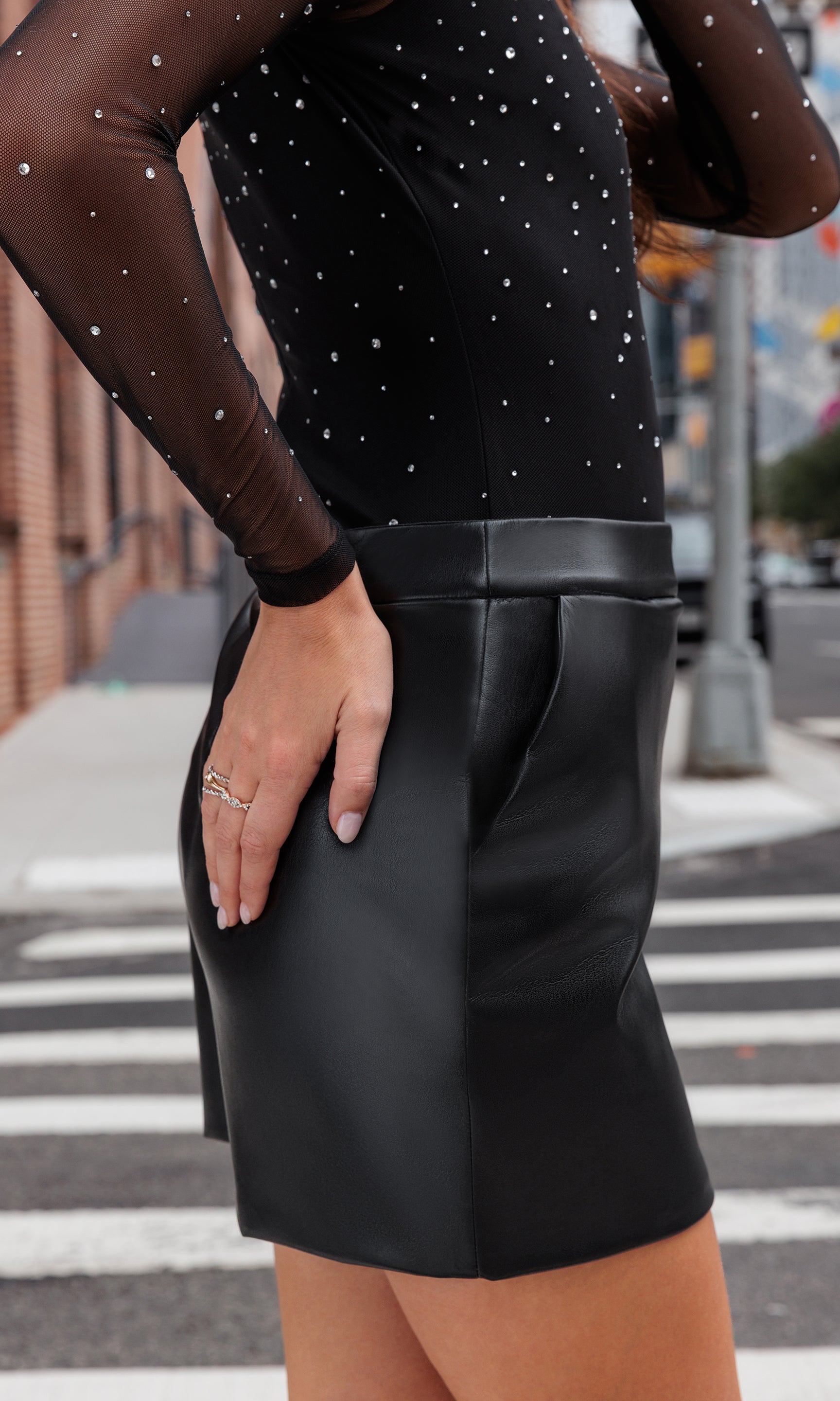 Close-up of model wearing a crystal studded top with a black vegan leather skirt