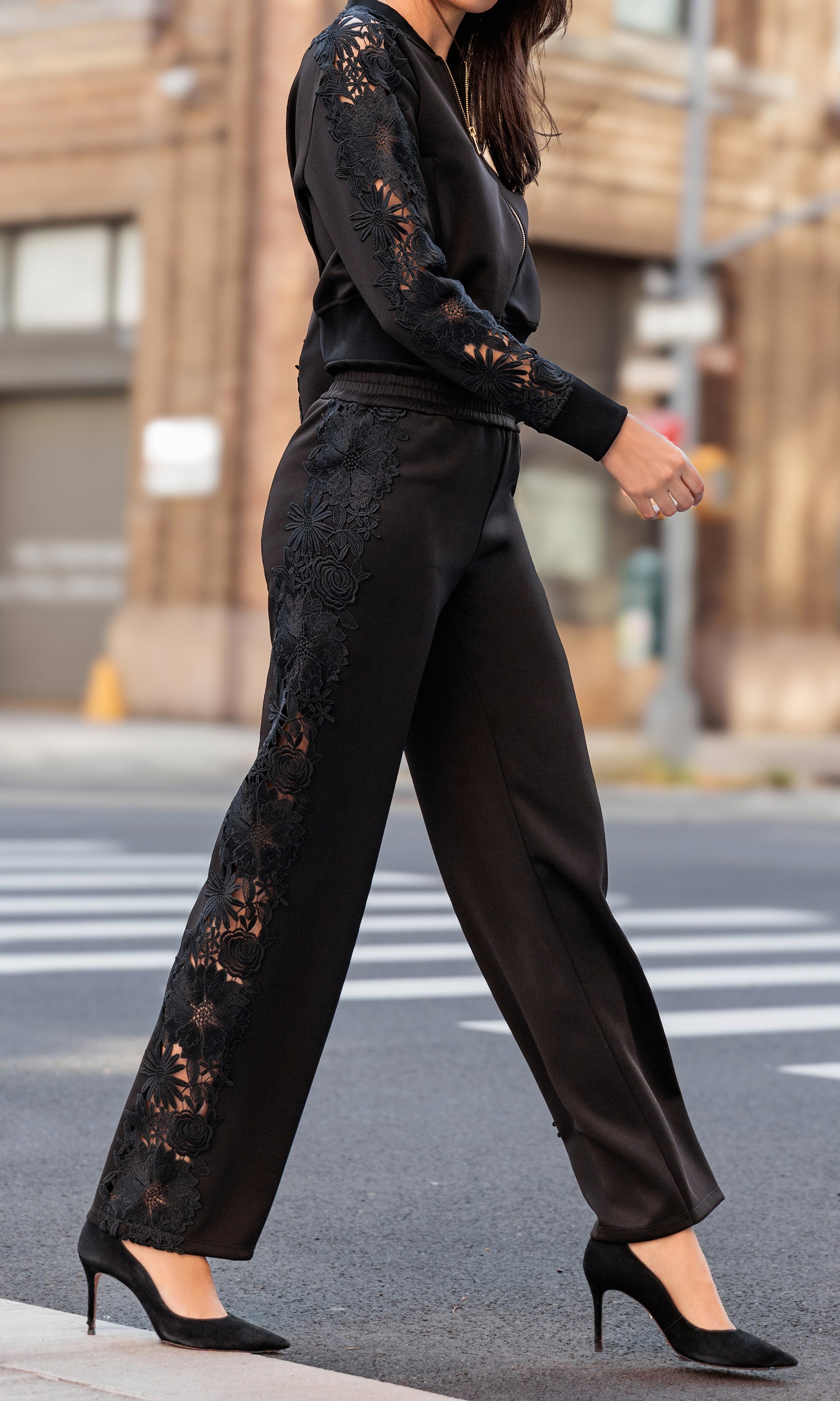 Person wearing a black lace outfit walking on a street.