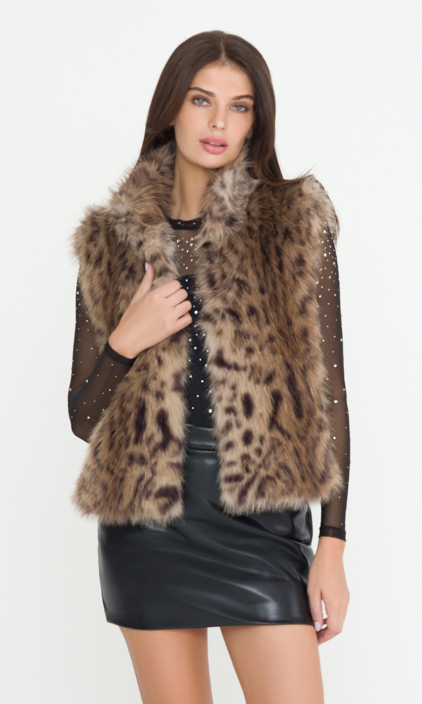 Woman wearing a leopard print fur vest with a plain background