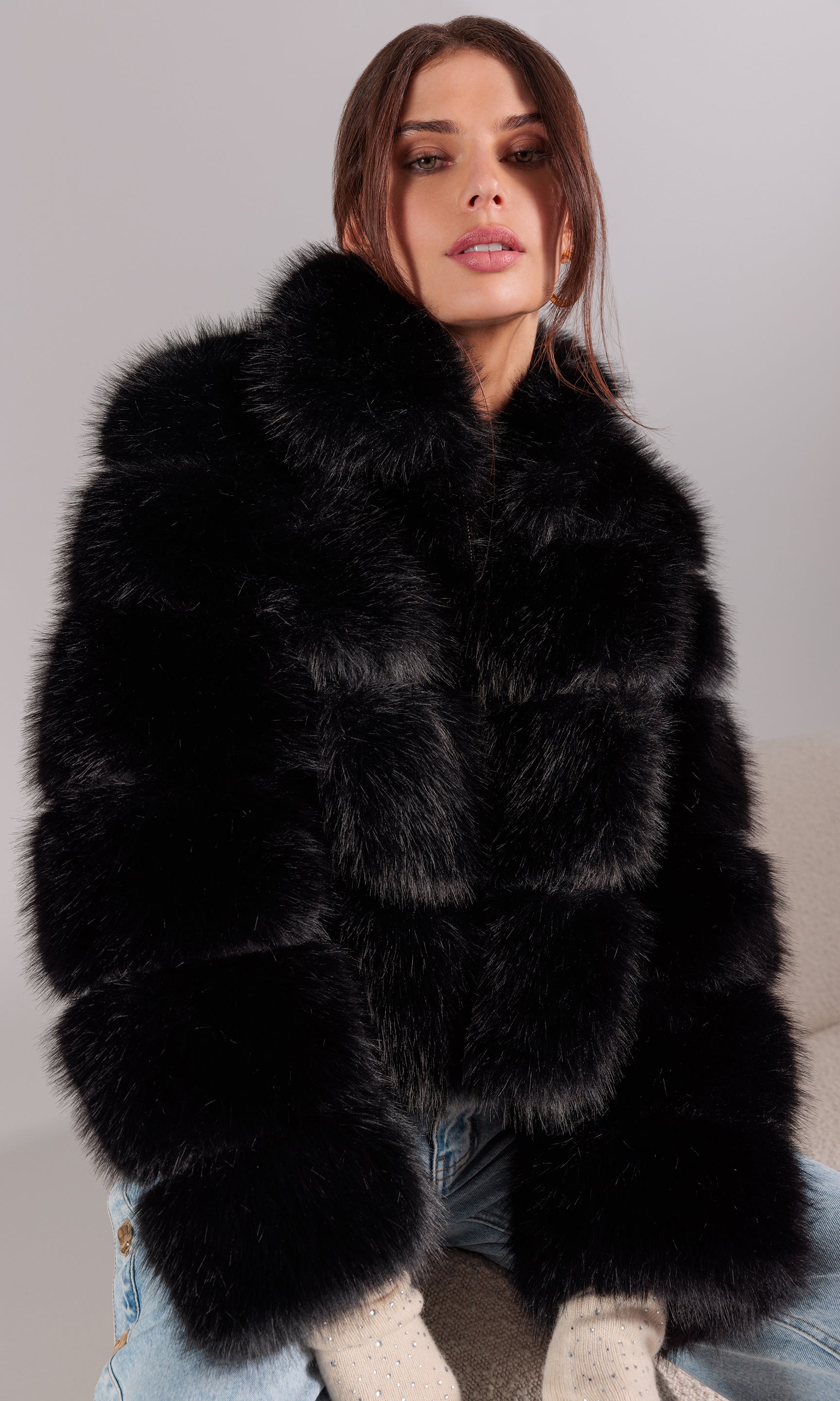 Woman wearing a black fur coat against a neutral background