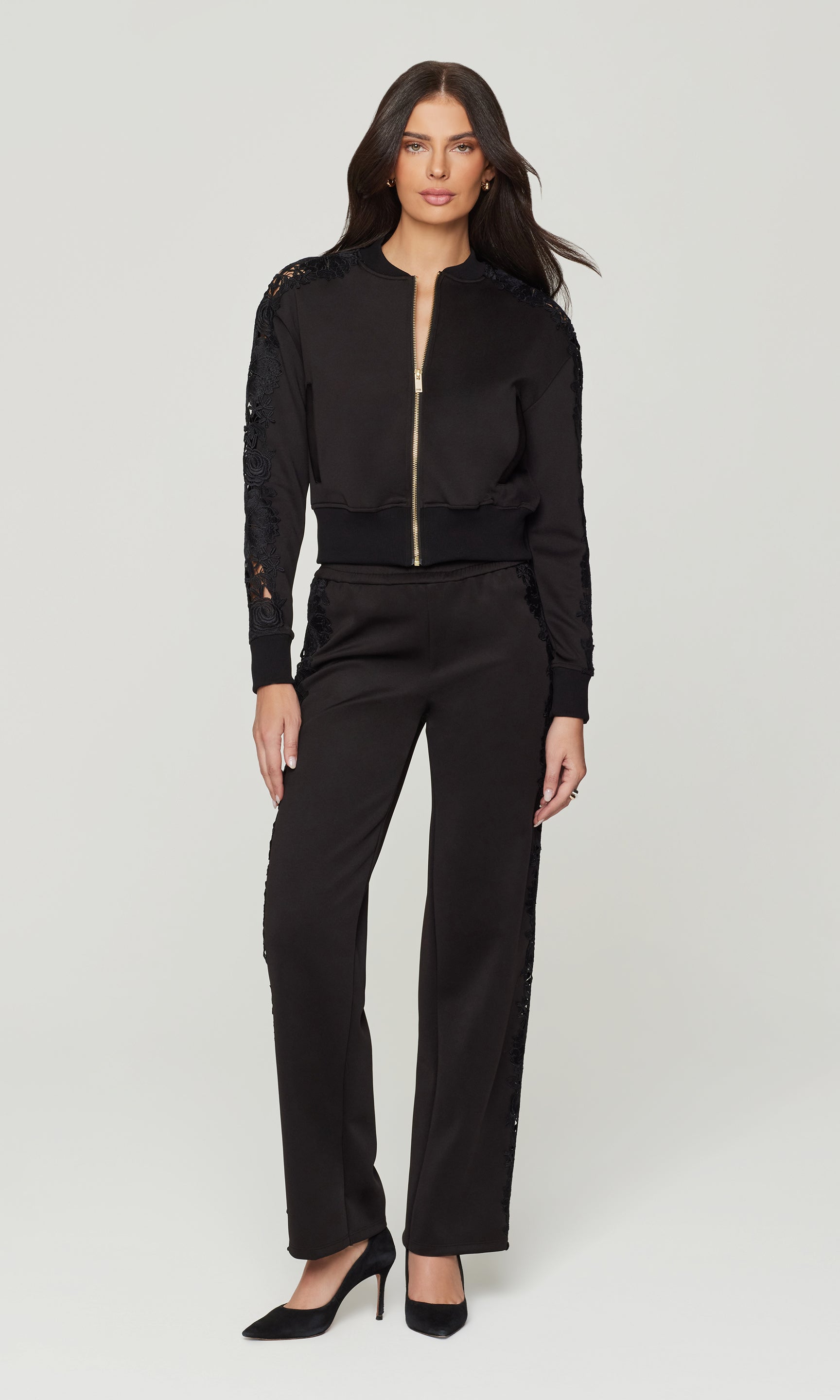 Woman wearing a black outfit with a jacket and pants on a white background