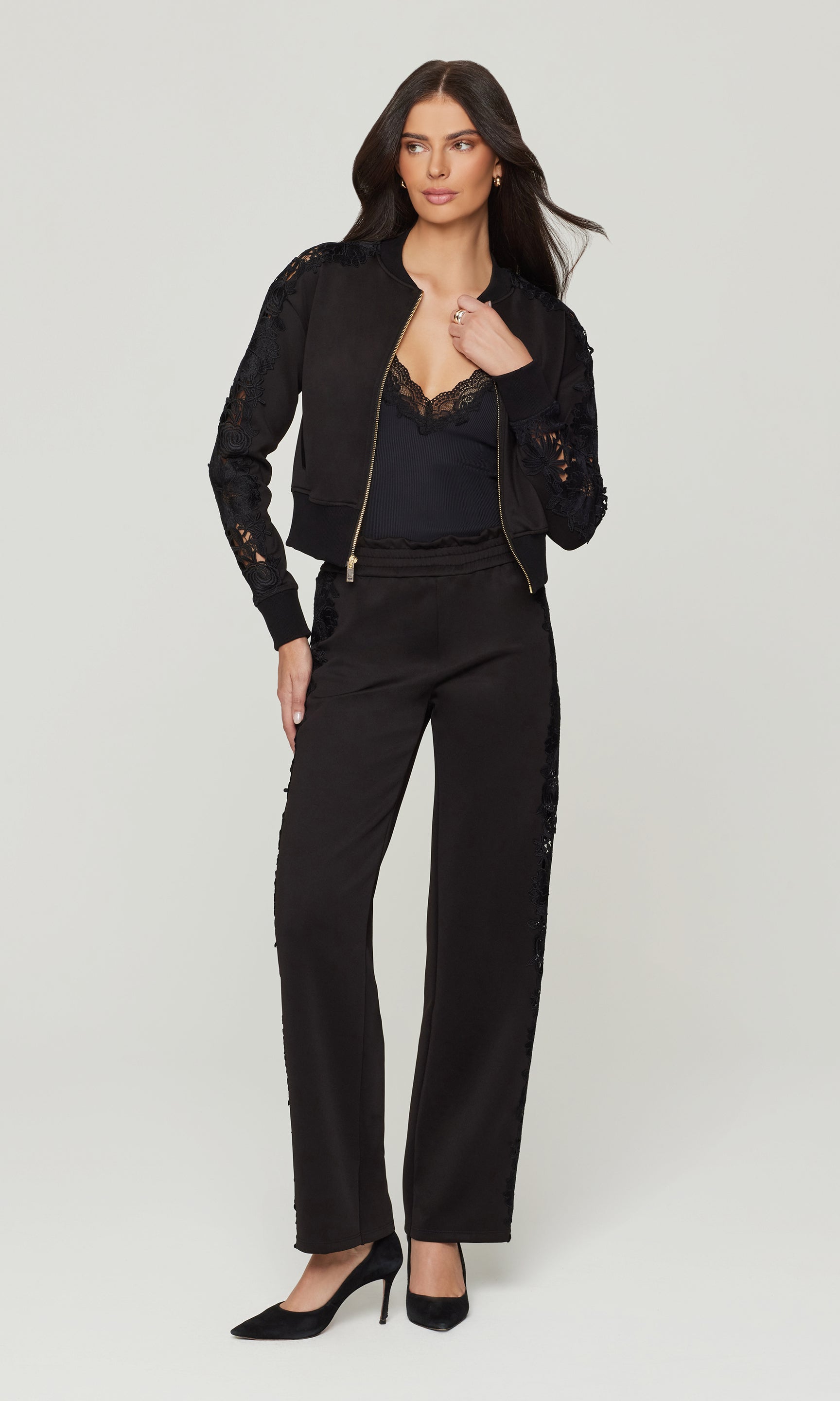 Woman wearing a black outfit with lace details on a white background