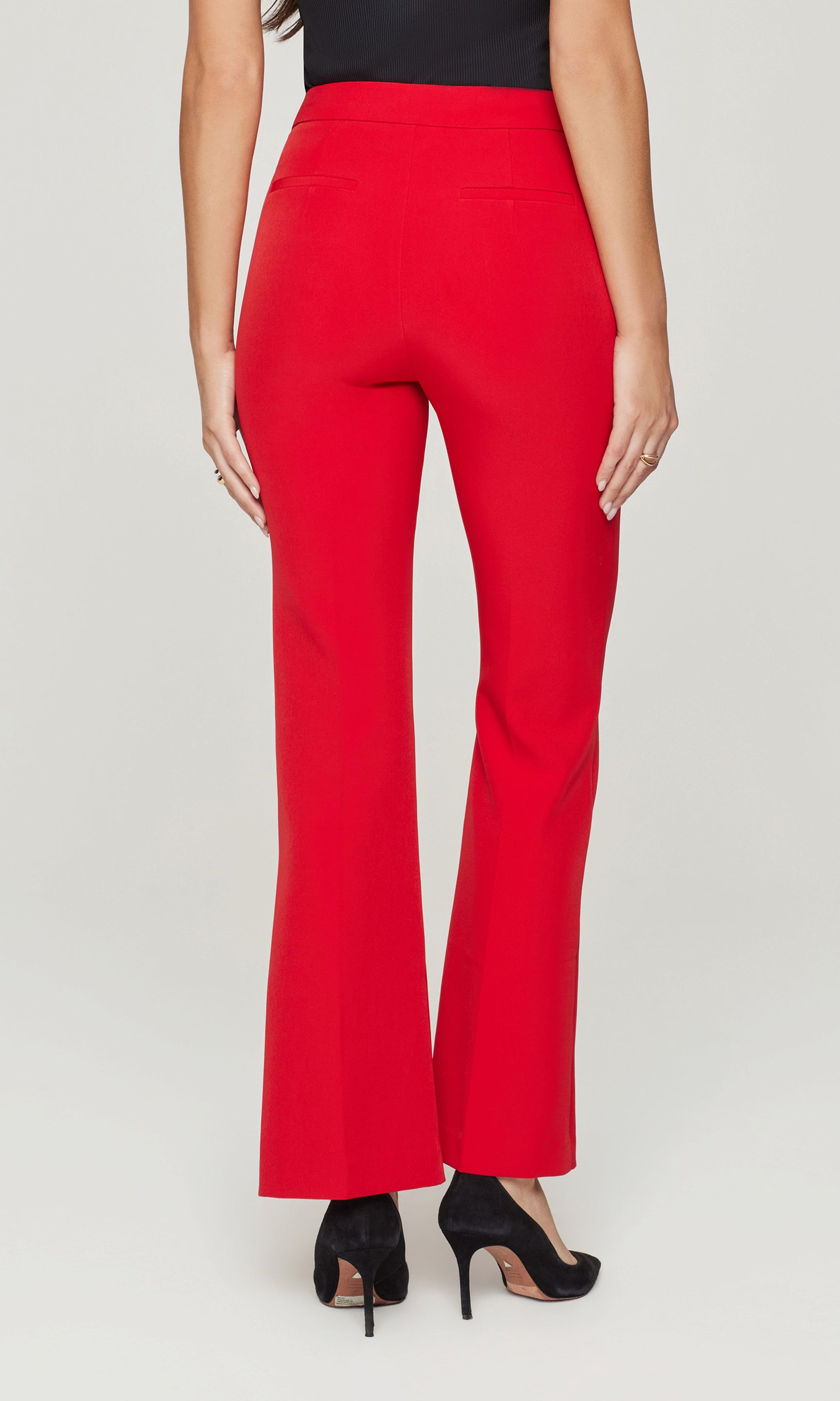 Back view of red pants worn by a person on a white background