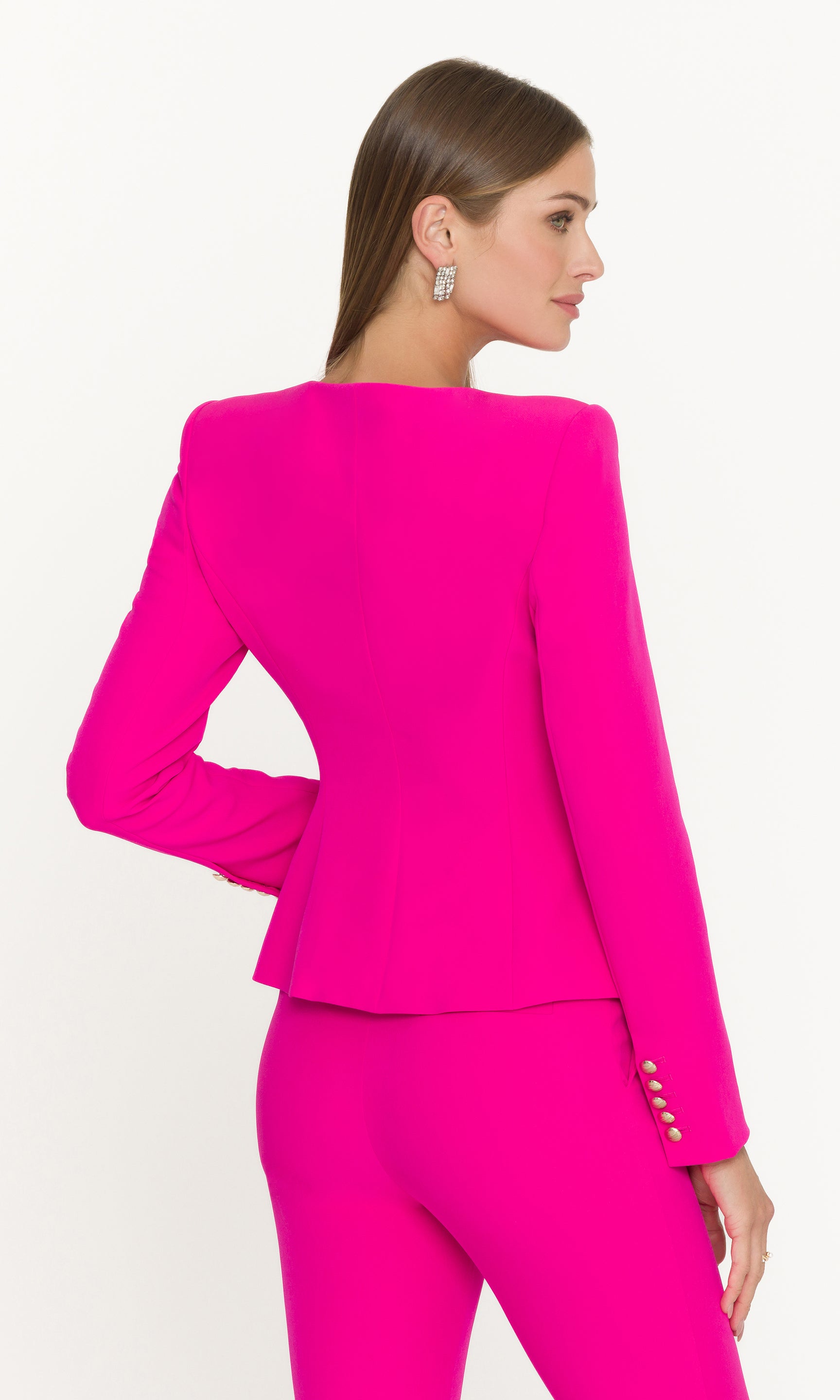 Back view of woman wearing a bright pink suit on a white background