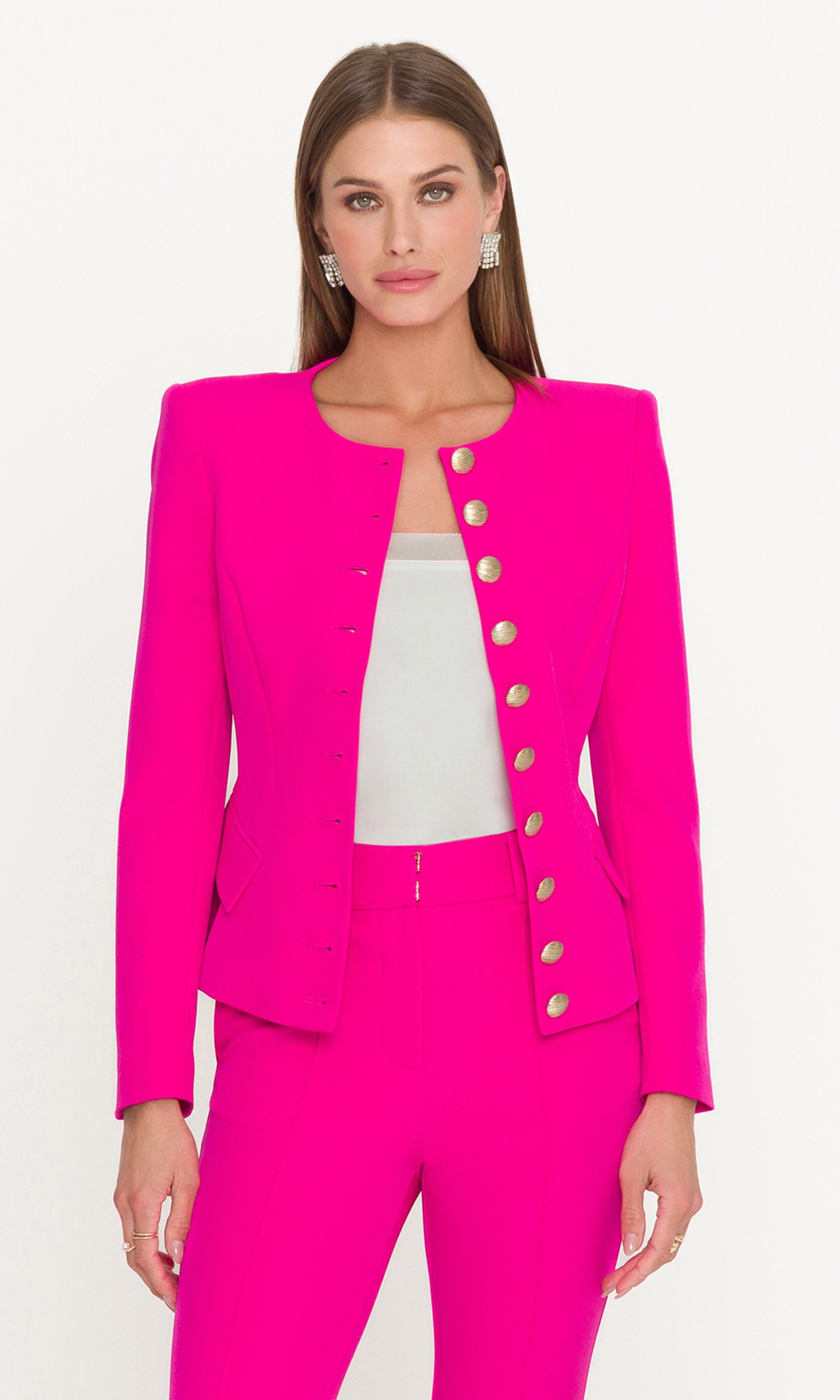 Model wearing a pink suit and white cami with a white background