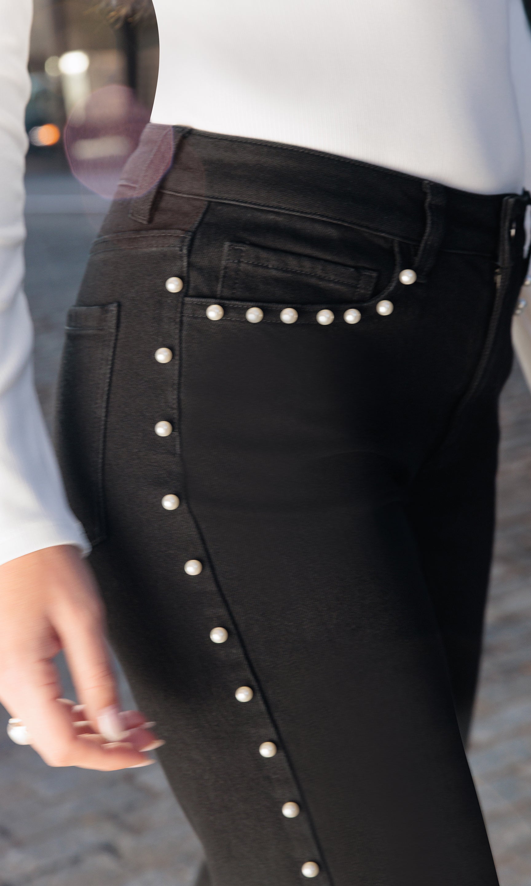 Black pants with pearl buttons on a blurred street background