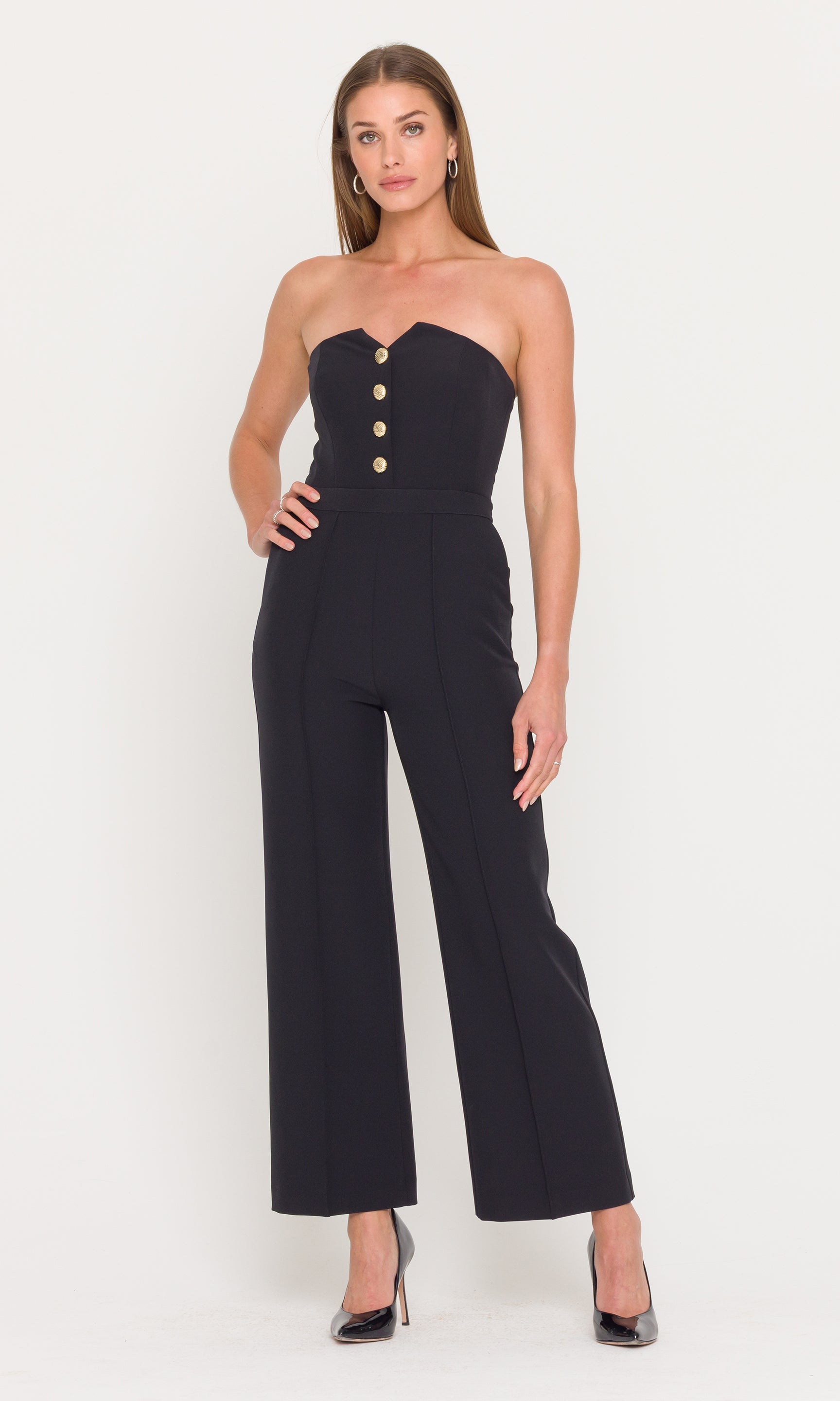 Woman wearing a black strapless jumpsuit with button details on a white background