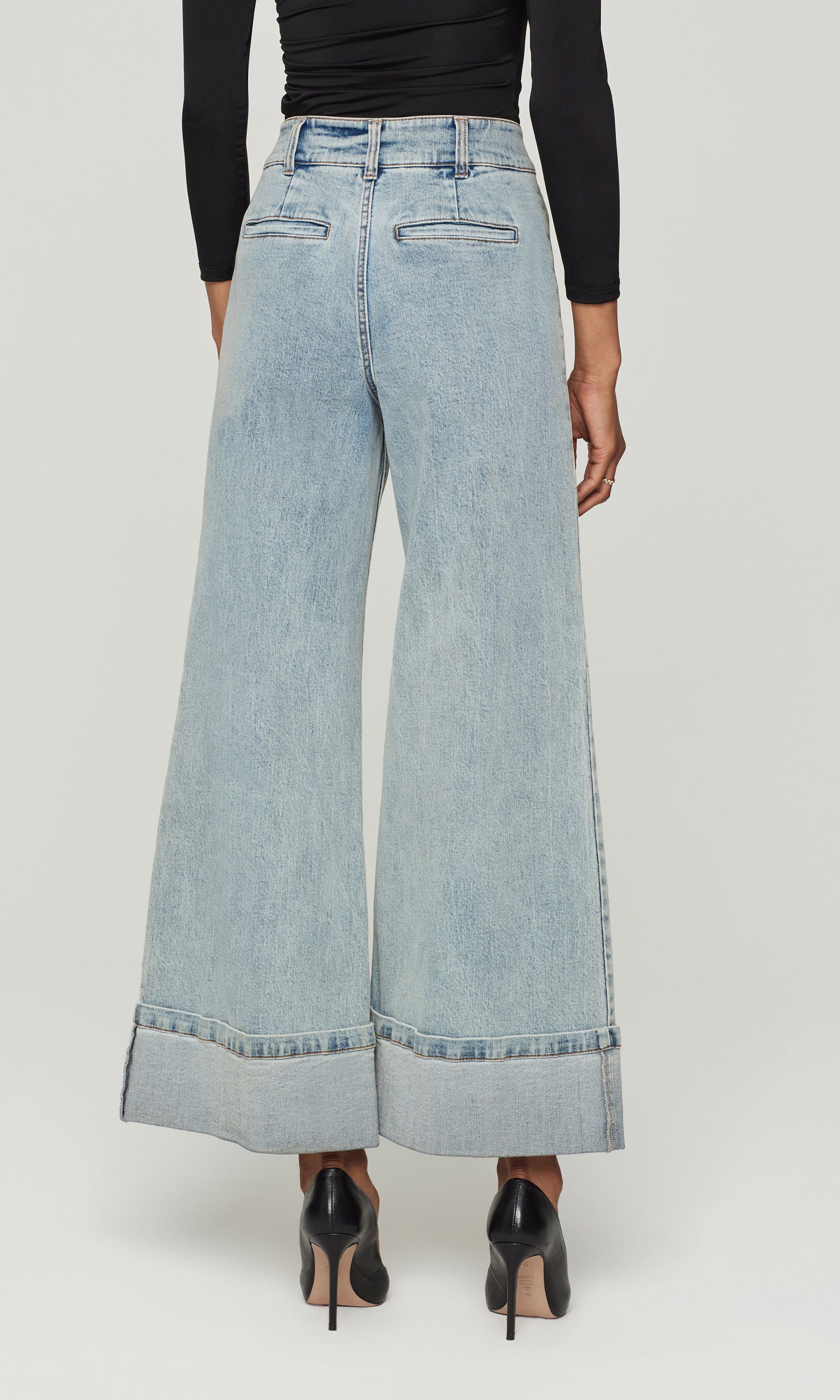 Back view of light blue wide-leg jeans worn by a person on a white background