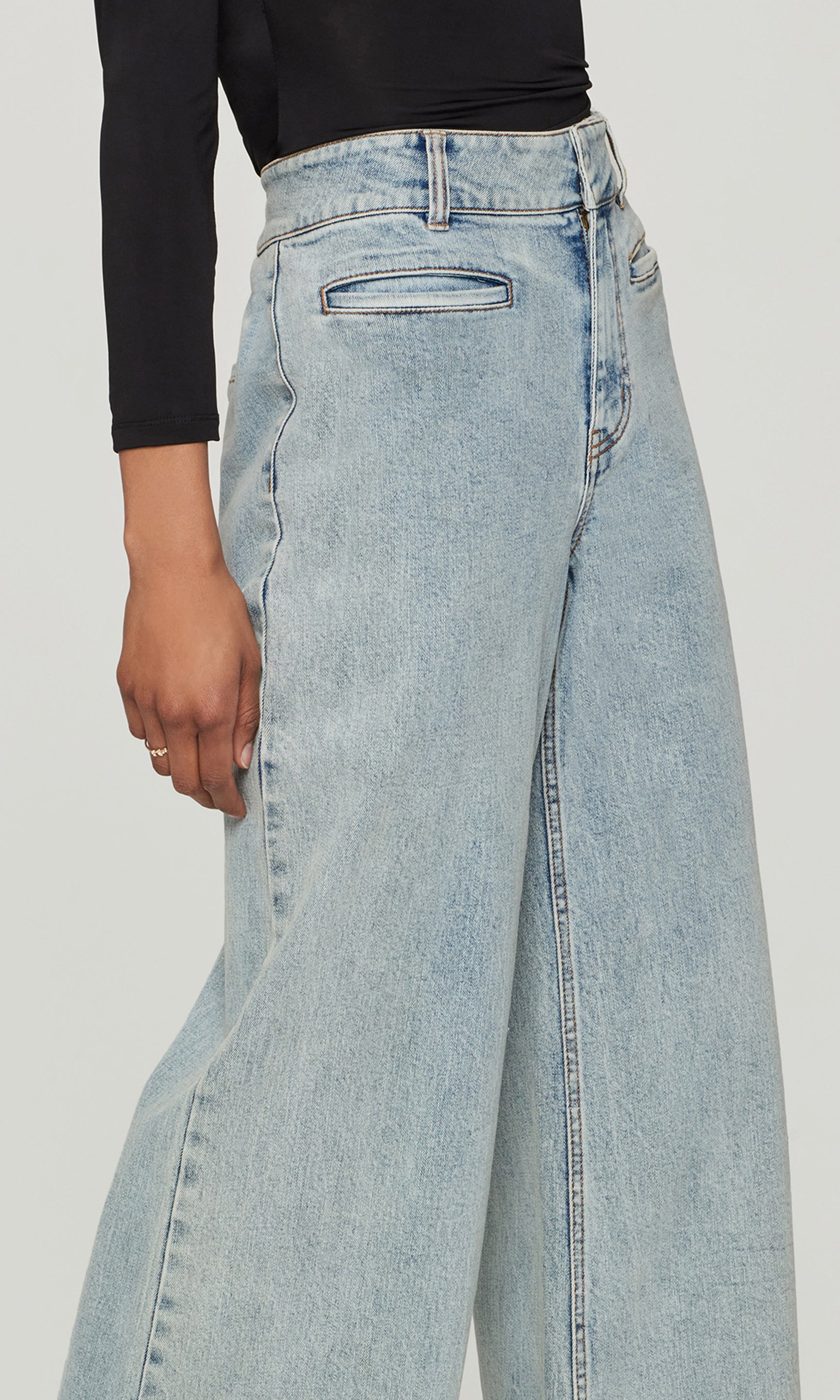 Close-up of light blue wide-leg jeans worn by a person on a white background