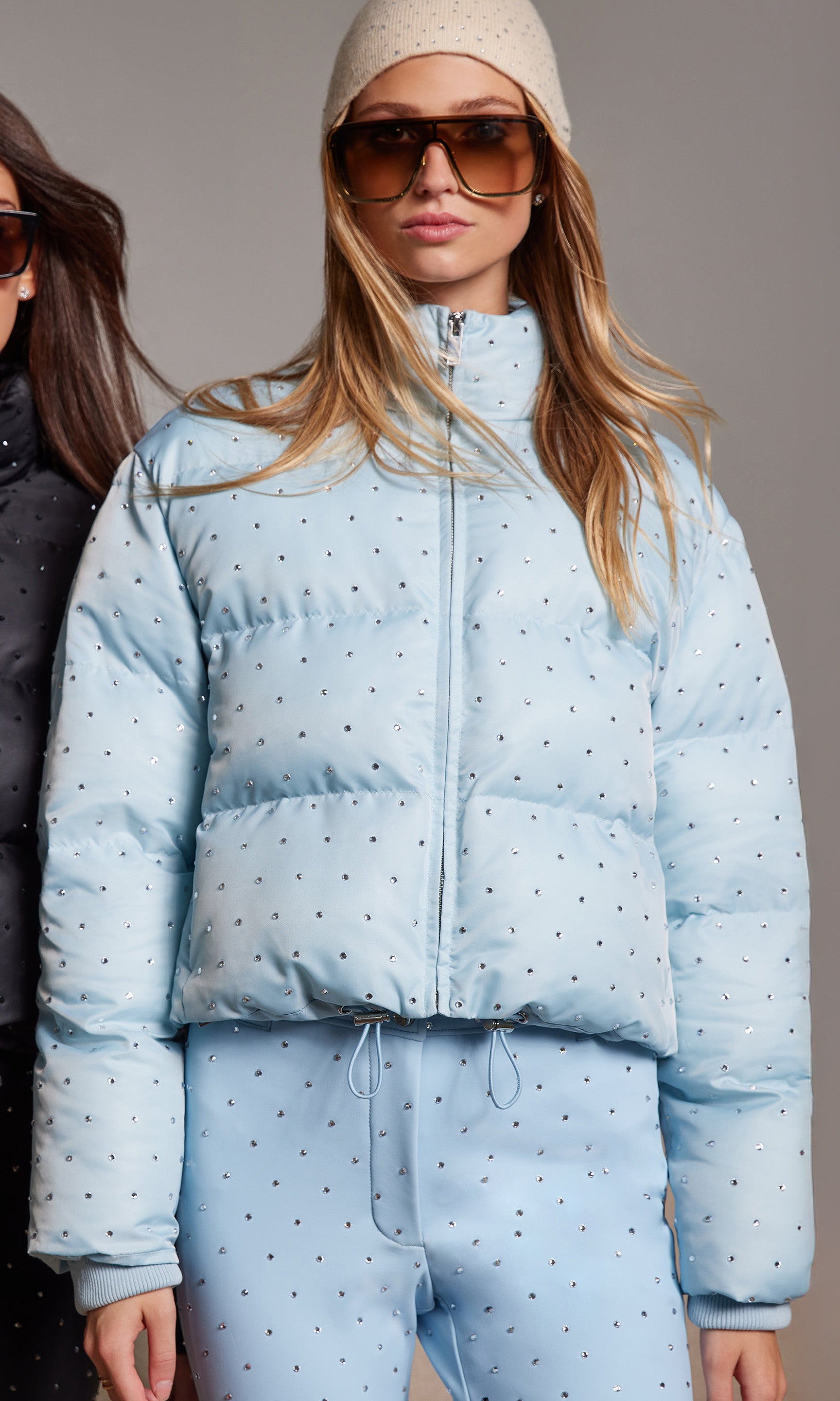 Woman wearing a light blue puffer jacket with crystals and matching pants.