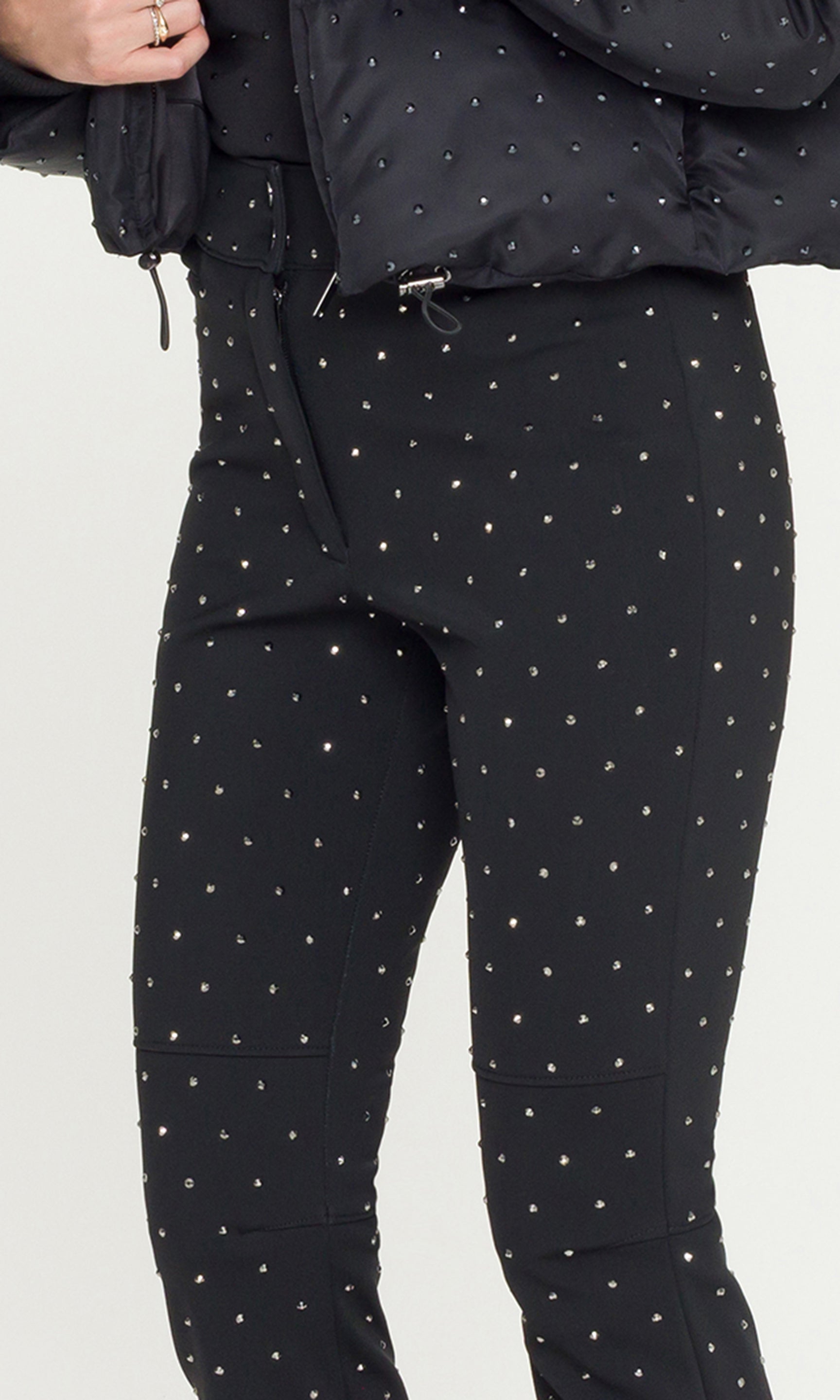 Close-up of model wearing black ski pants with crystal embellishments and a matching jacket