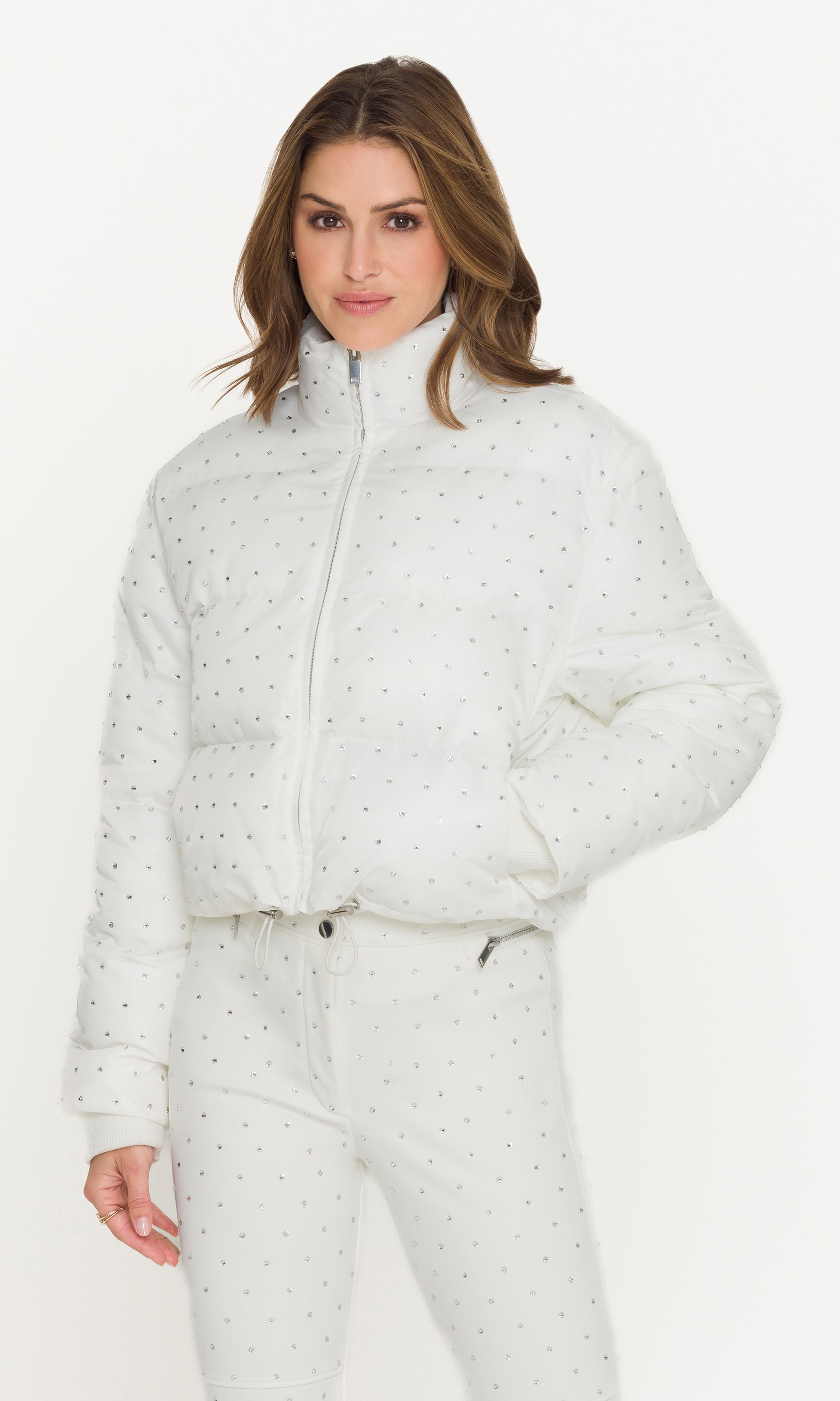 Woman wearing a white puffer jacket with a subtle pattern on a white background