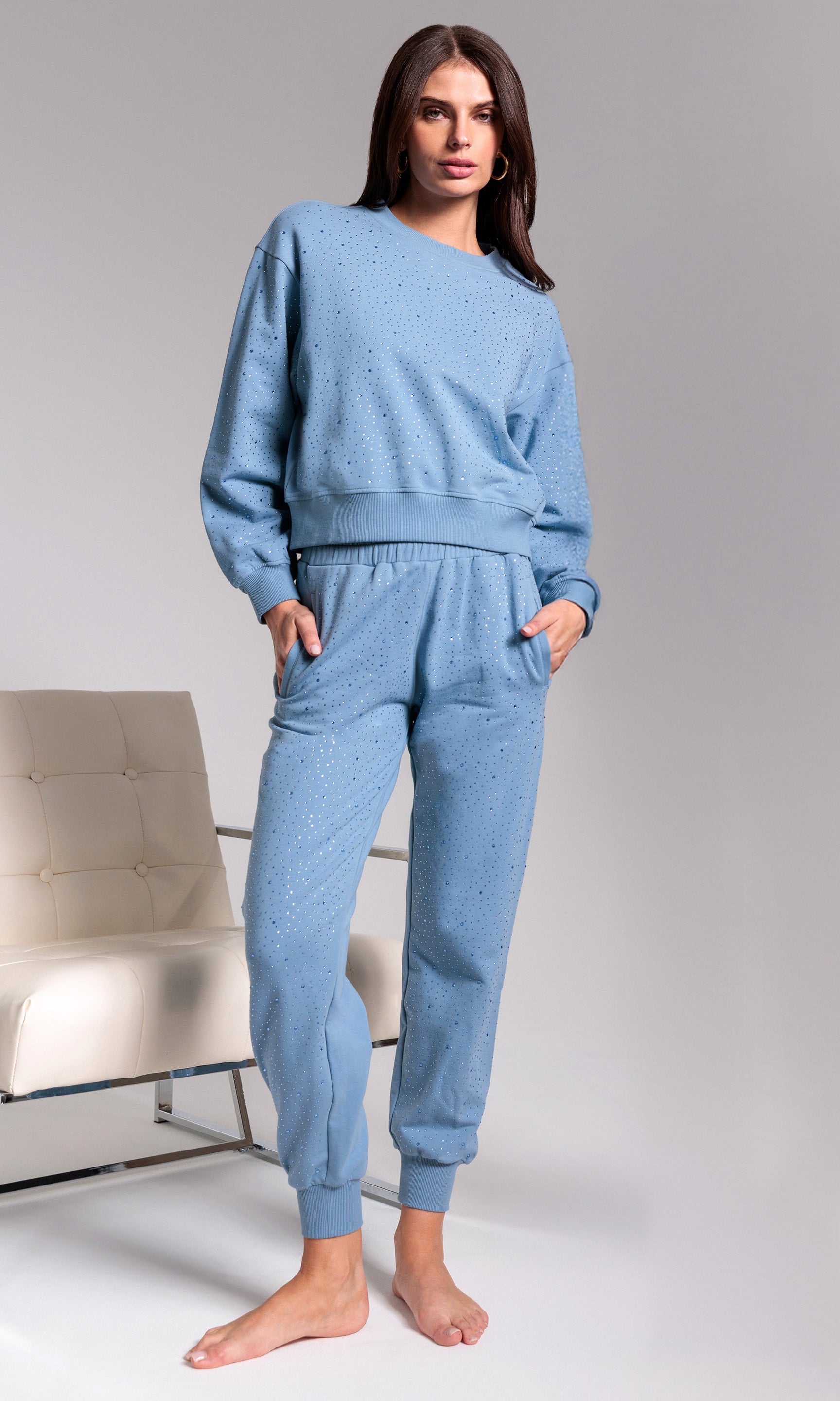 Woman wearing a blue tracksuit against a gray background