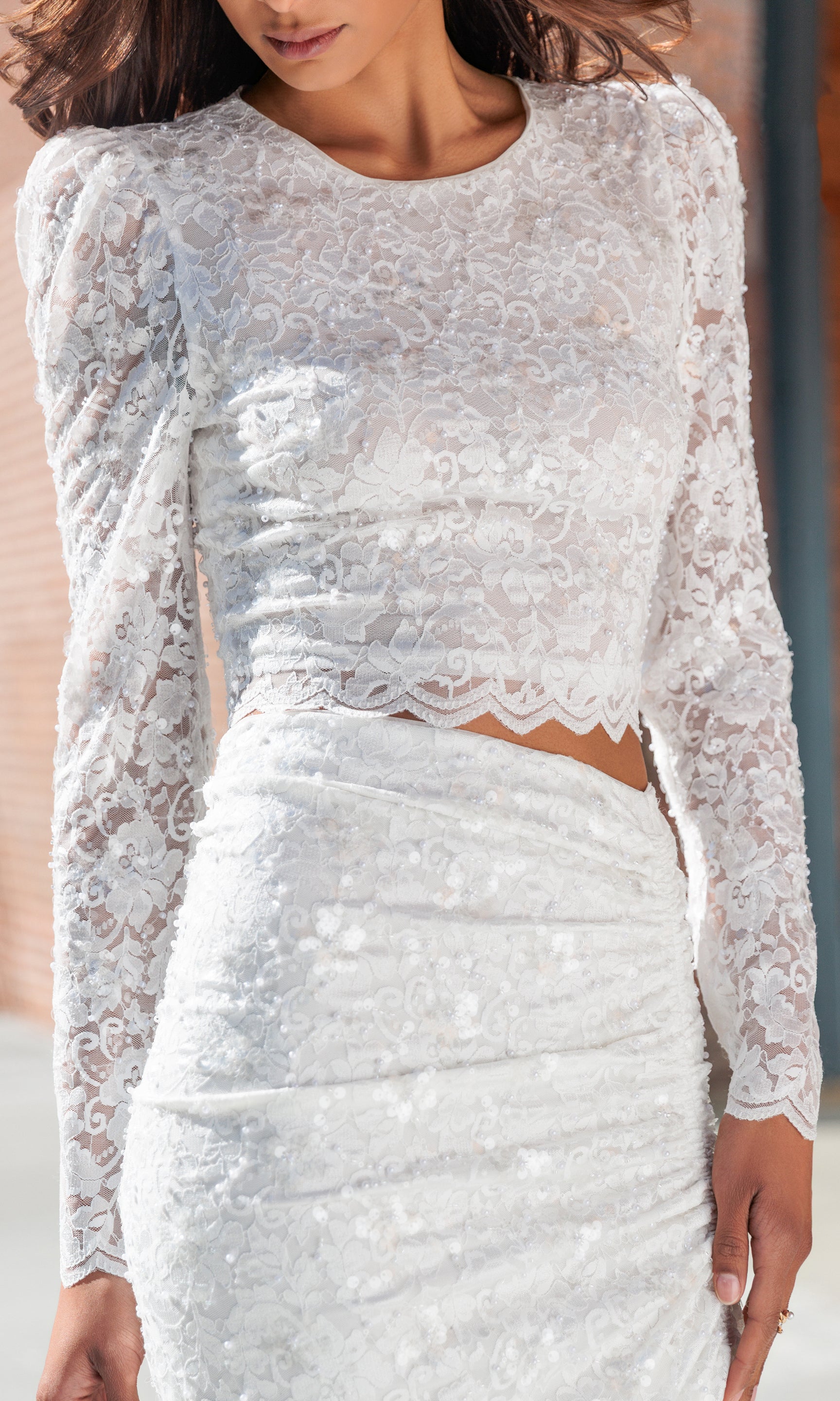 White lace two-piece outfit with long sleeves on a blurred background