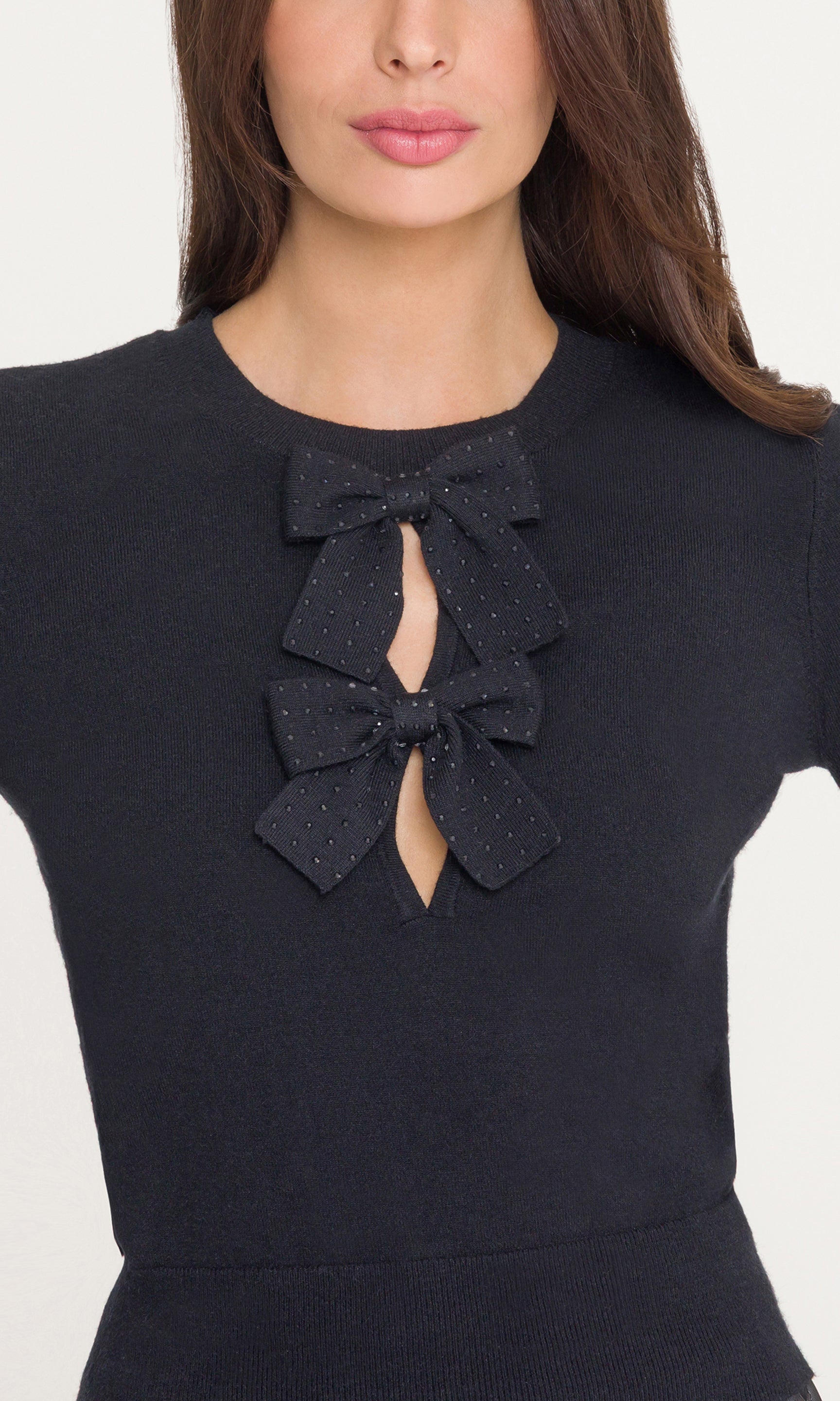 Close-up of black top with bow details on a white background