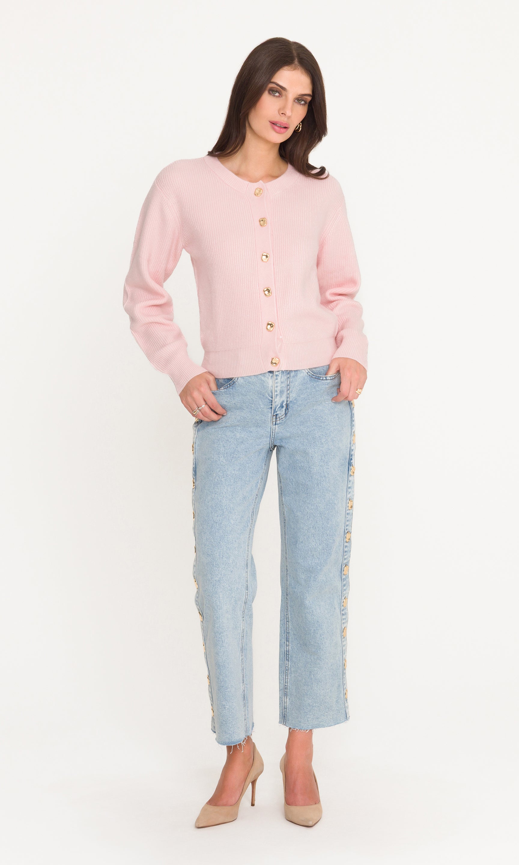 Woman wearing a pink cardigan and light blue jeans on a white background