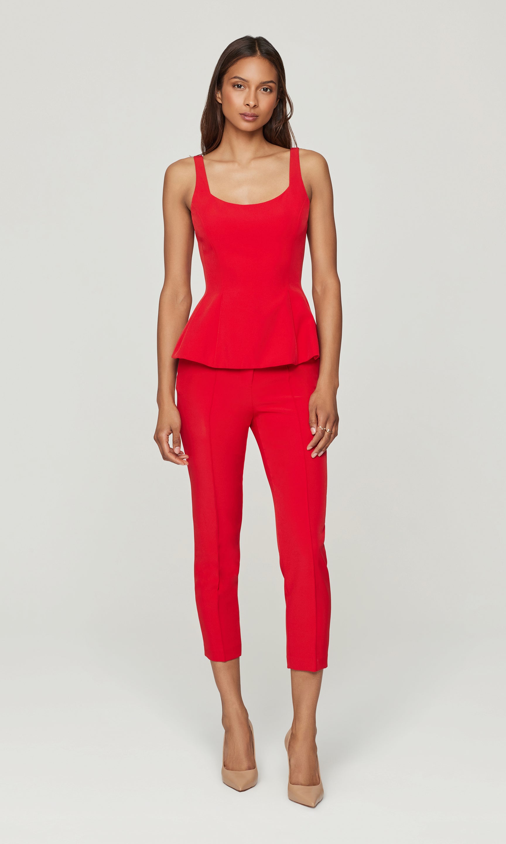 Woman wearing a red peplum top and pants on a white background