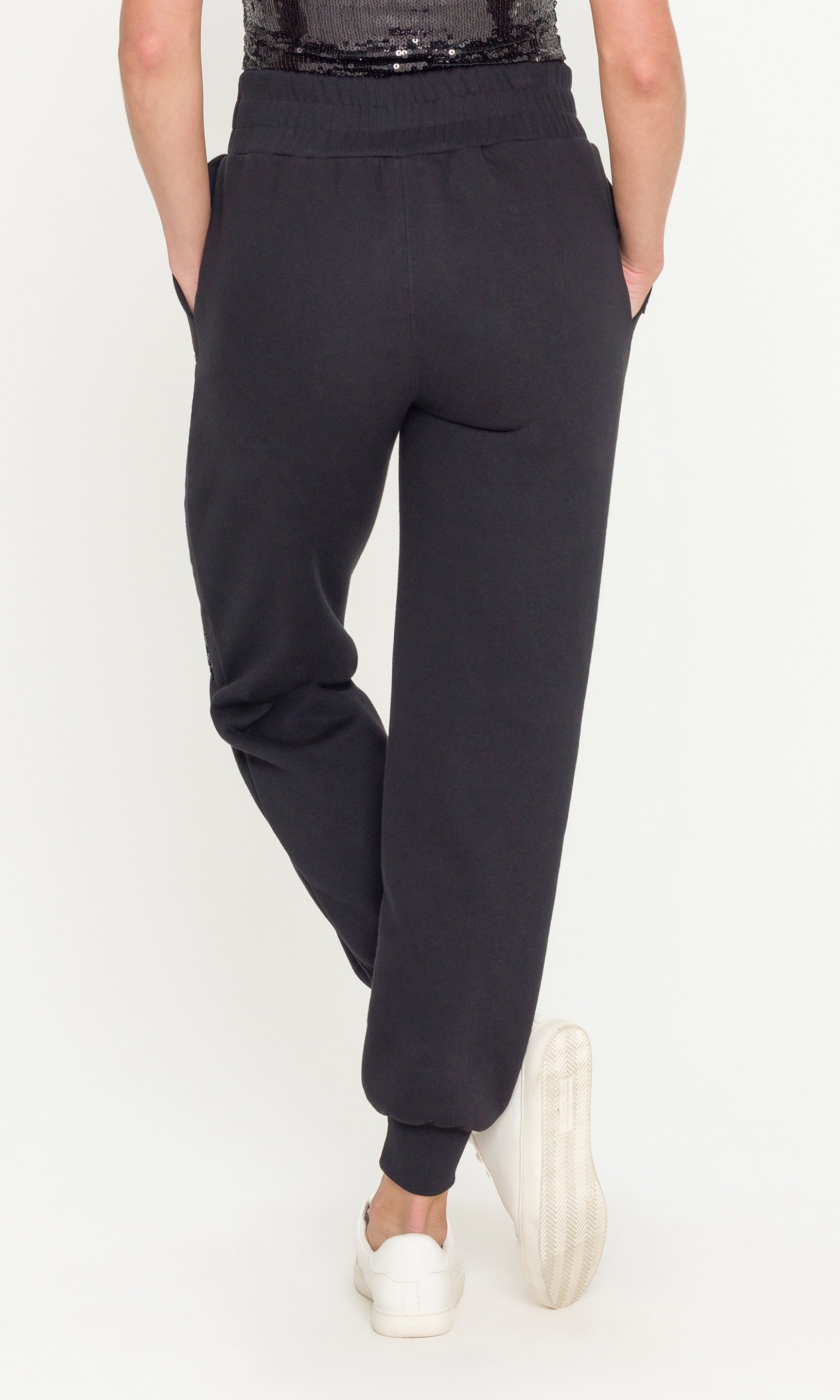 Black jogger pants worn by a person on a white background
