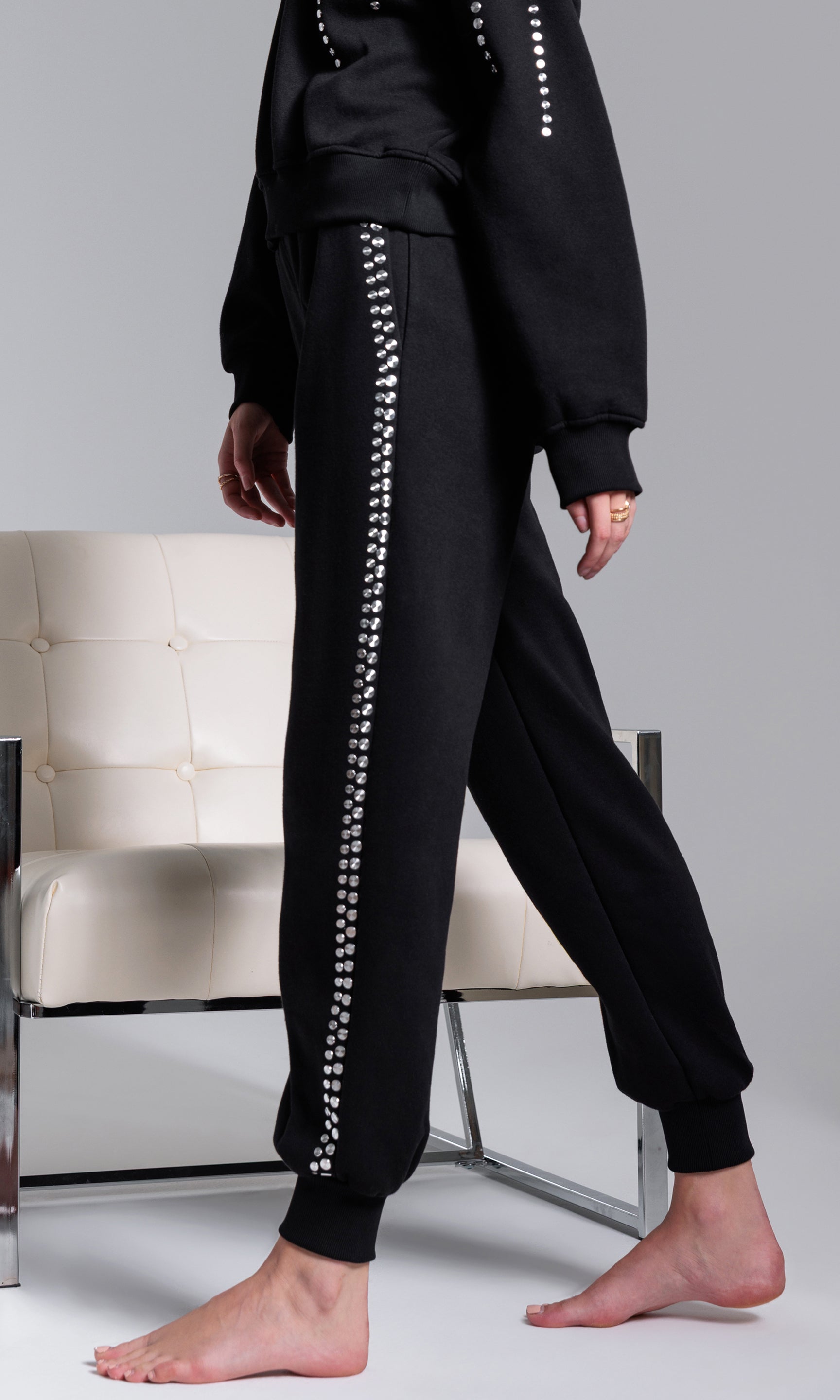 Black tracksuit with silver studs details on a neutral background