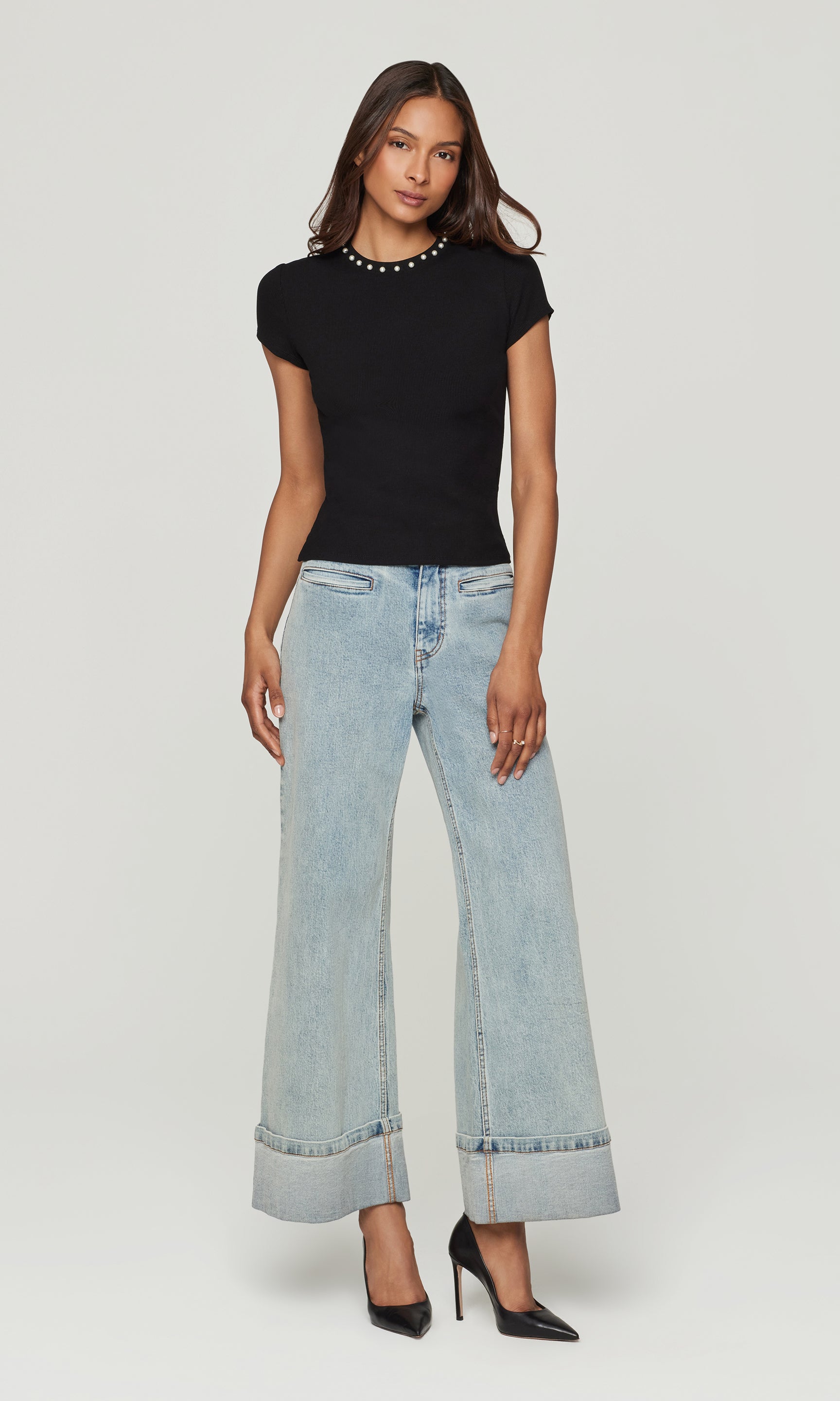 Woman wearing a black top and light blue jeans on a white background