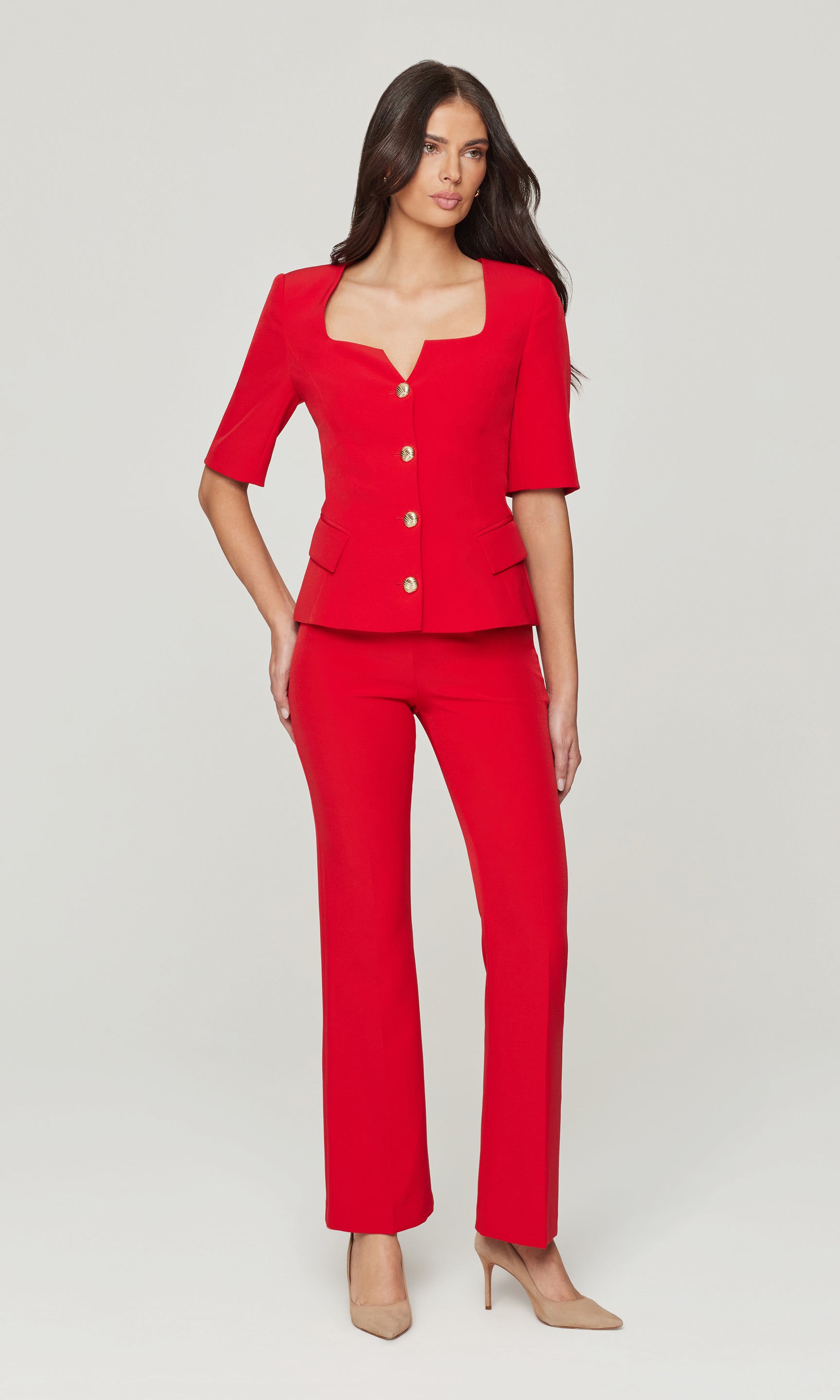 Woman wearing a red outfit with a matching jacket and pants on a white background