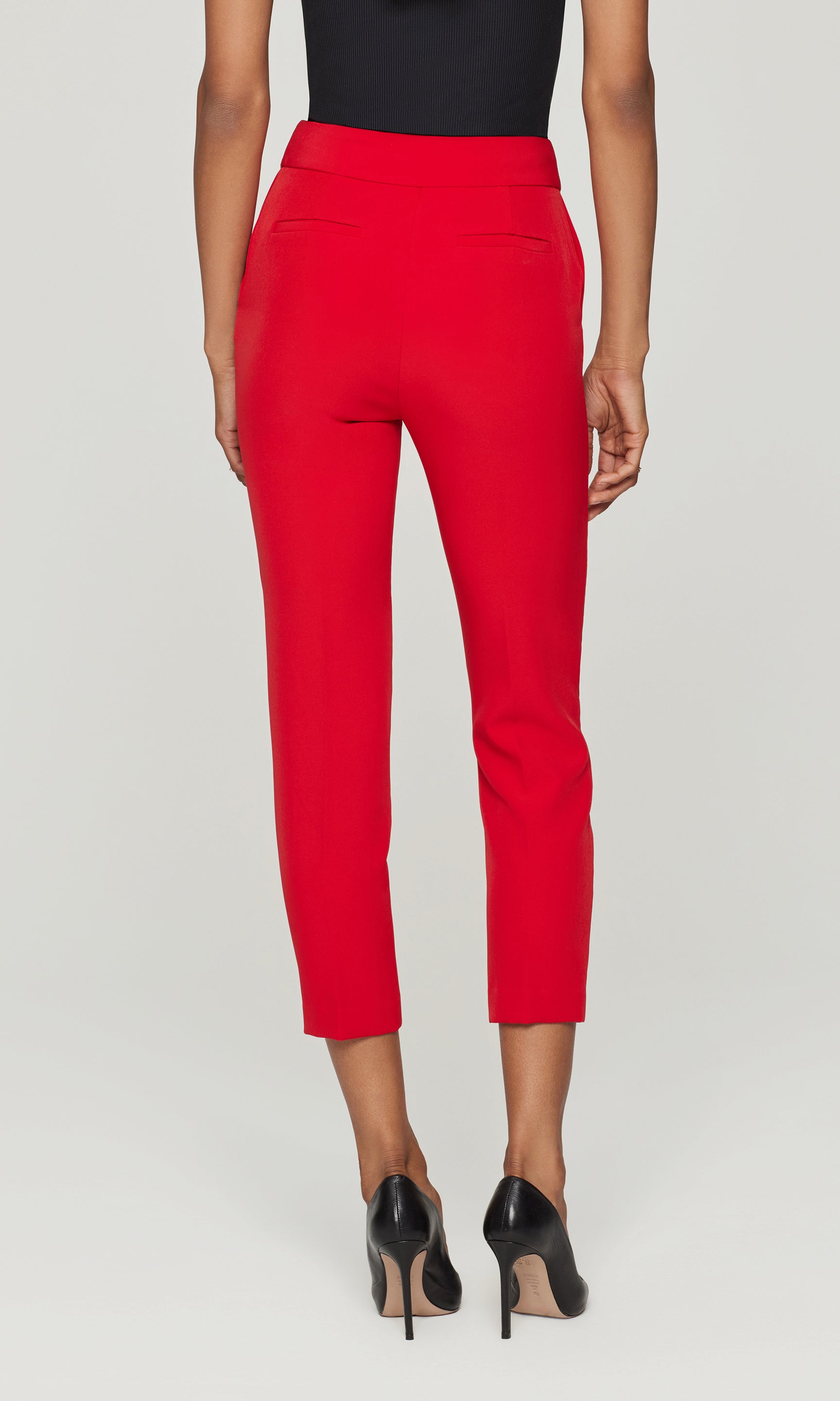 Back view of red pants worn by a person on a light gray background